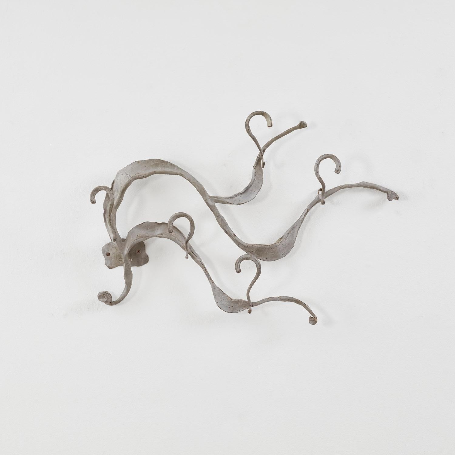 Fluide, rythmée, ondulante, Onde est une suspension murale sculpturale nommée d'après le mouvement des vagues, complétée par des crochets courbes qui s'enroulent autour de chaque forme ondulée. 

La pièce est en bon état et présente une patine