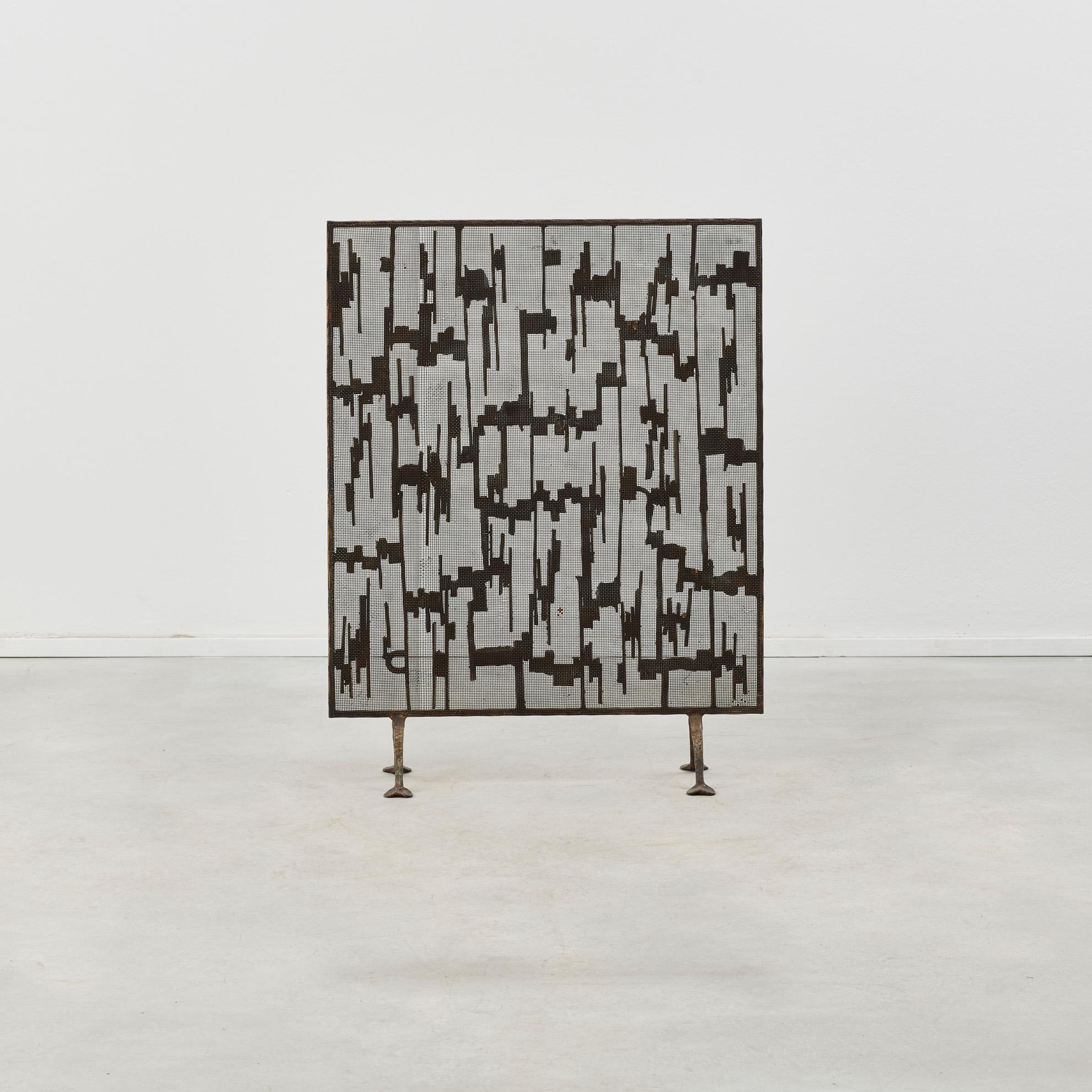 El carácter irregular de la pantalla rectangular refleja el interés de Marsura tanto por el Art Nouveau como por el Brutalismo. Elementos verticales de hierro que representan esbeltas estalactitas están sujetos a una malla de alambre fino, revelando