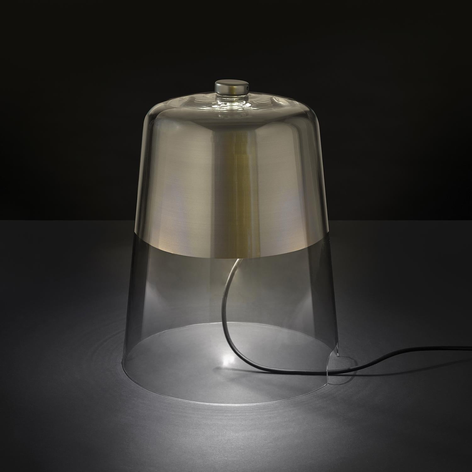 Table lamp 'Semplice' designed by Sam Hecht in 2013.
Able lamp giving reflected light in transparent blown glass. Turned internal aliminium reflector. ON/OFF power control with knob on top of the glass.
Manufactured by Oluce, Italy.

Sam Hecht