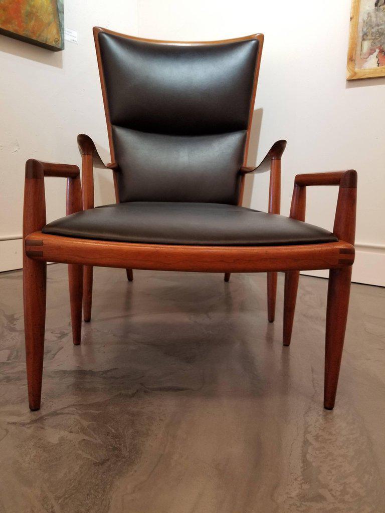 A sculptural black walnut lounge chair and accompanying foot stool by Sam Maloof. Excellent original condition, beautiful glow to original finish. Newly upholstered in black leather. Both pieces signed. Foot stool measures: 23.88