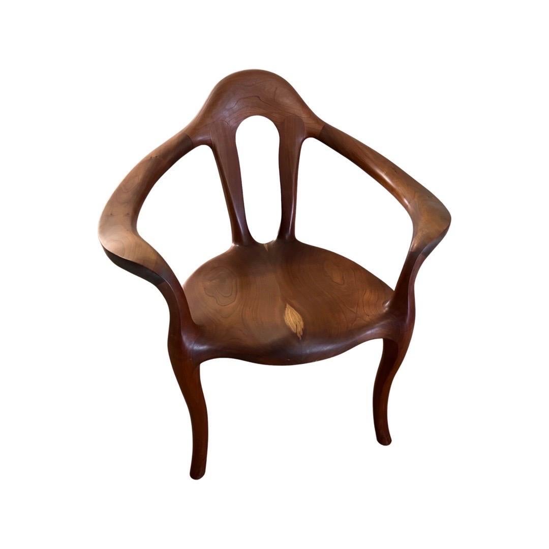 Ein außergewöhnlicher, handgefertigter Sessel, inspiriert von der weiblichen Form. Dieser bemerkenswerte Sessel aus Nussbaumholz hat einen frei fließenden Körper, eine solide Konstruktion und ist auf der Unterseite mit 