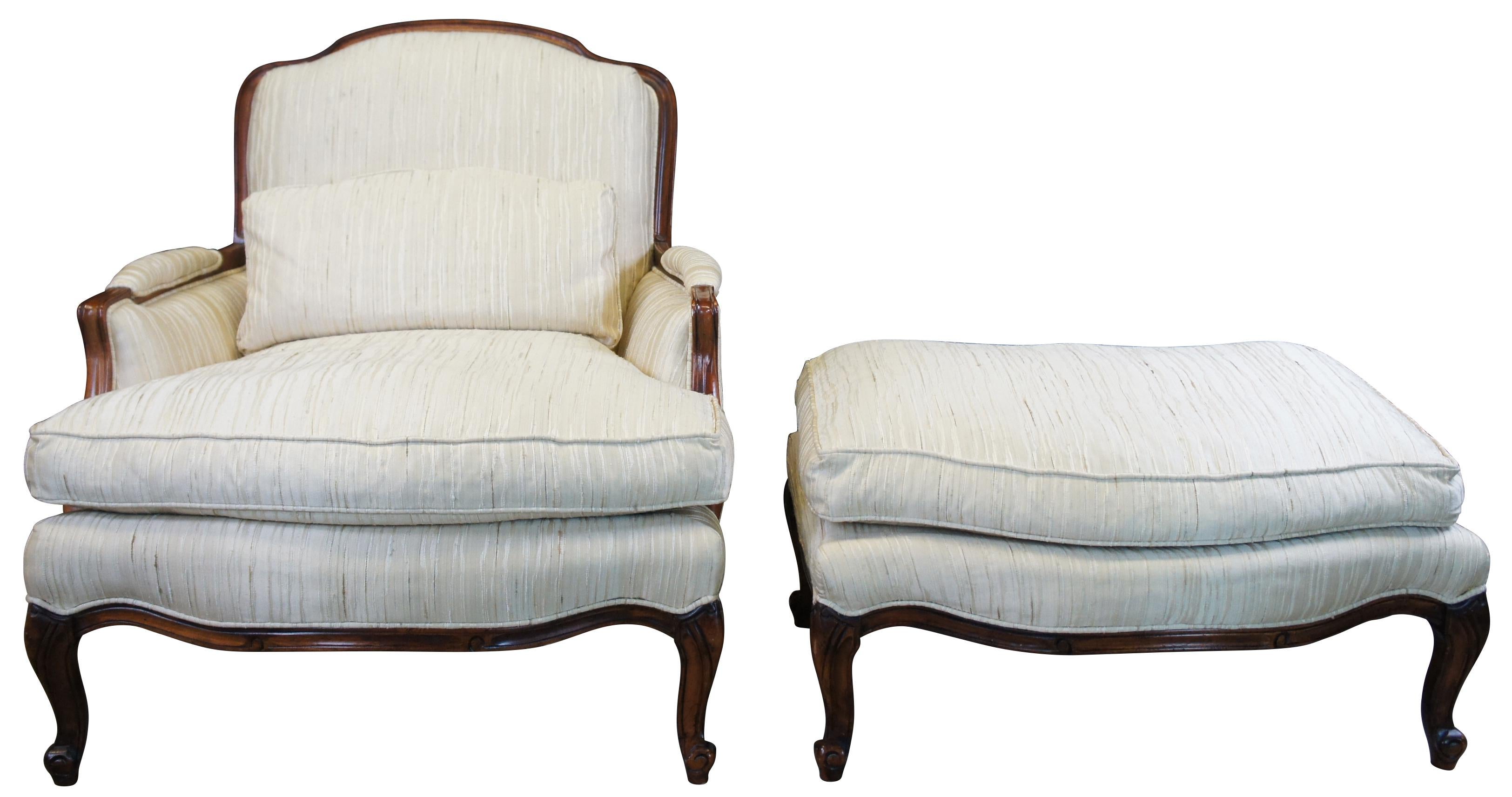 Vintage bergere armchair and ottoman by Sam Moore Furniture Industries of Bedford Virginia, circa 1987. Made of naturally distressed walnut featuring French styling with serpentine form, padded arms and cabriole scrolled feet. Ember Finish, 821