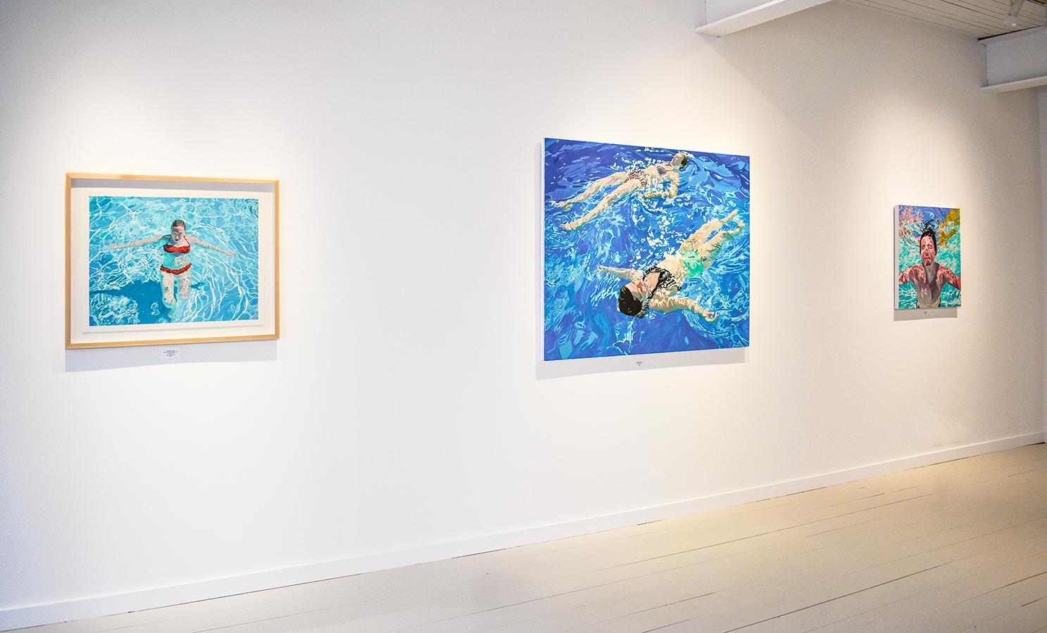 Square figurative photo-realist painting of an underwater view of a young man swimming in an aqua blue pool
