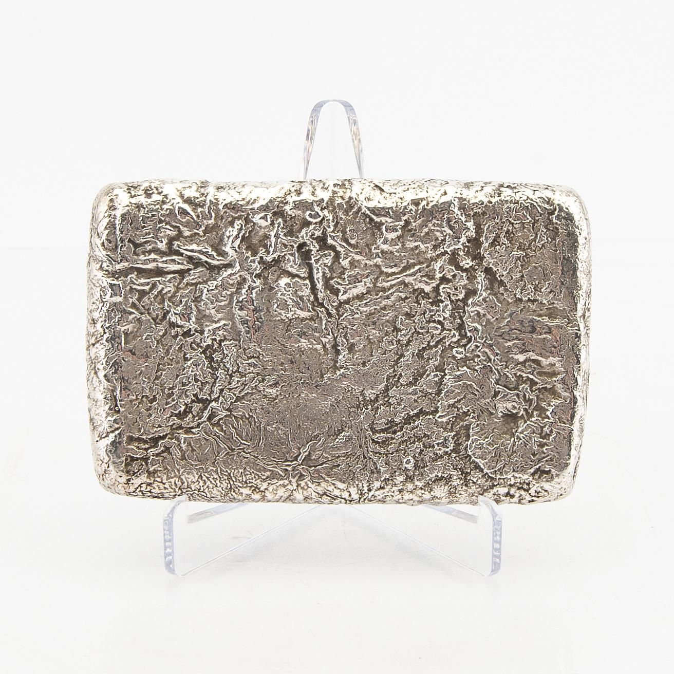 A Russian Silver Samodorok Cigarette Case Early 20th Century Russia.
the textured silver case with an inset brown red hardstone cabochon thumb piece.
God gilded interior 
Wear commensurate with age and use. Unidentified maker's mark.