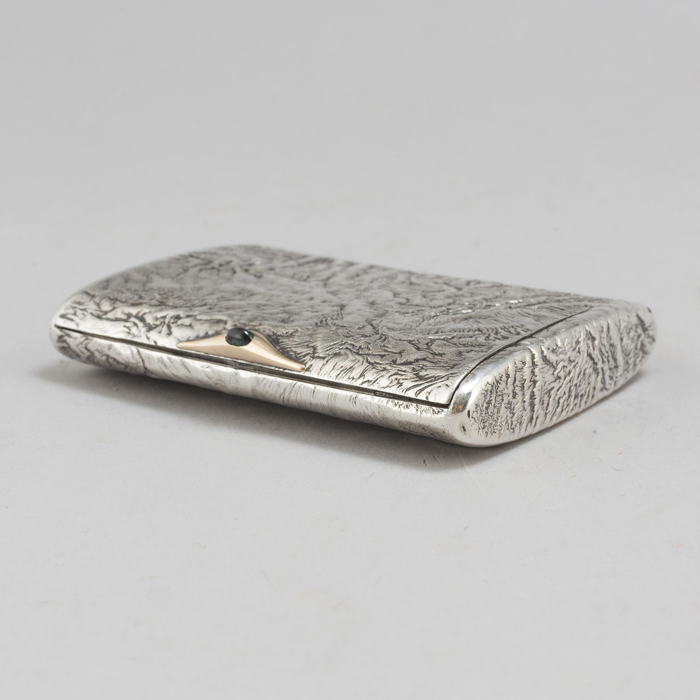 A parcel gilt samorodok  silver cigarette case by Vladimir Gordon S.t Petersburg,  with green stone, c.1900
Embossed signature.. A Fine quality Russian silver cigarette case. Reticulation  Samodorok was a technique used by many pre-revolution era