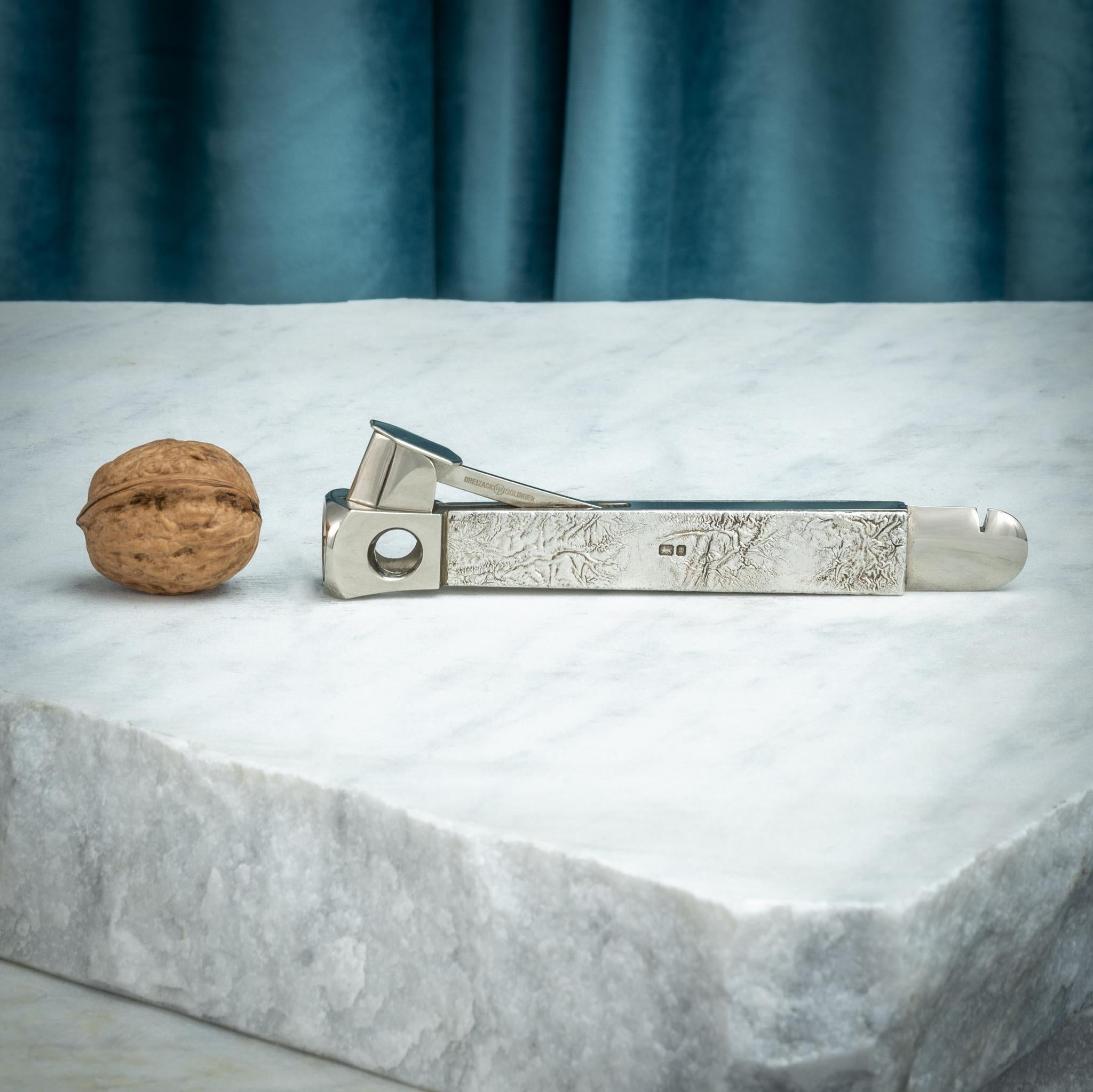 An unusual cigar cutter covered with reticulated 'Samorodok' silver, hallmarked, London 1977. With steel blade by the famed knife-maker, Wüsthof Dreizack from Solingen, Germany. The back end of this cigar cutter also has a tool for opening the