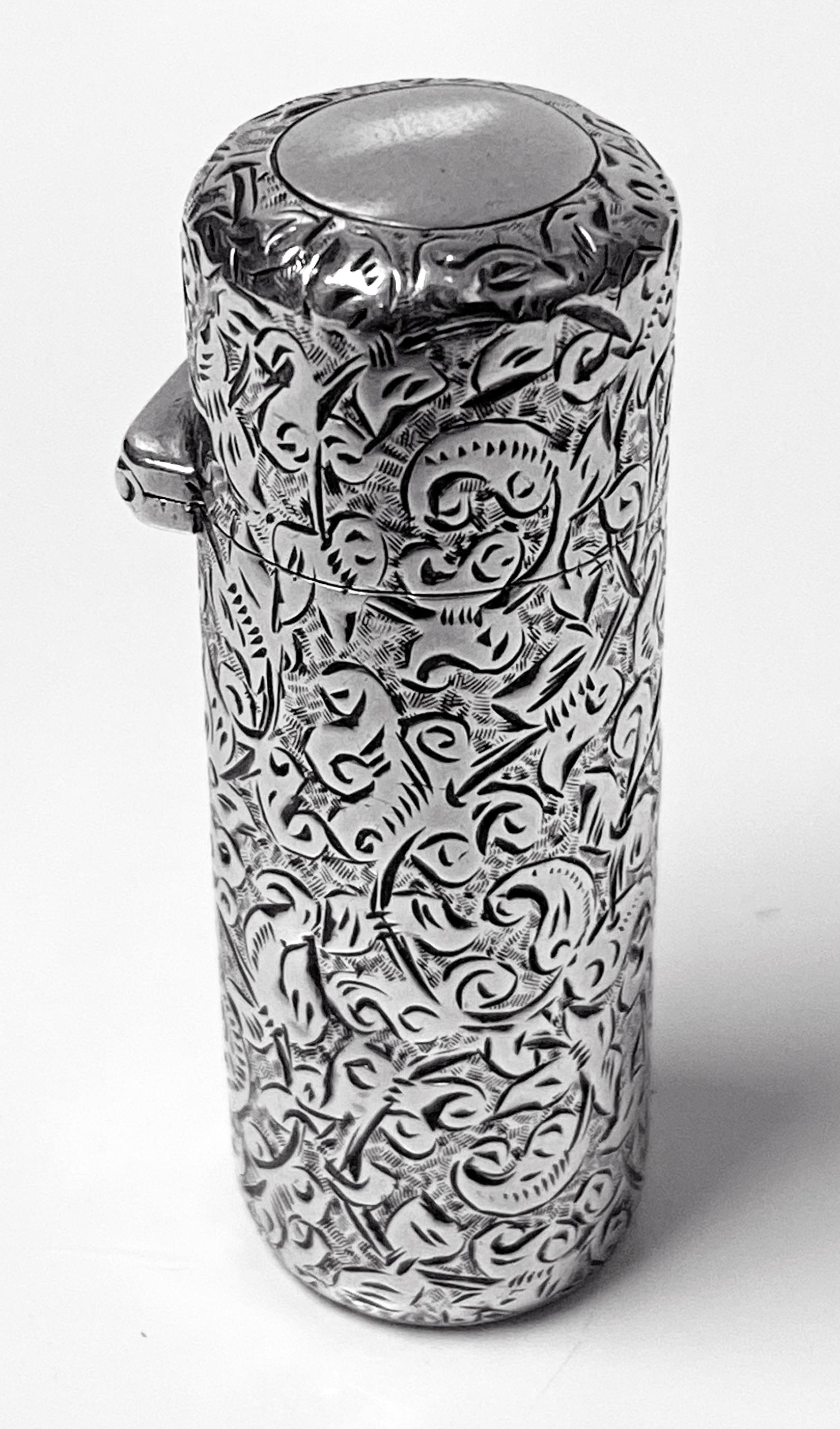 Sampson Mordan silver scent perfume bottle, London, 1888. Cylinder shaped, silver scent bottle, with a hinged top, vacant cartouche, no monograms, glass liner and glass stopper. The bottle is finely engraved with swirling scrollwork and stylized