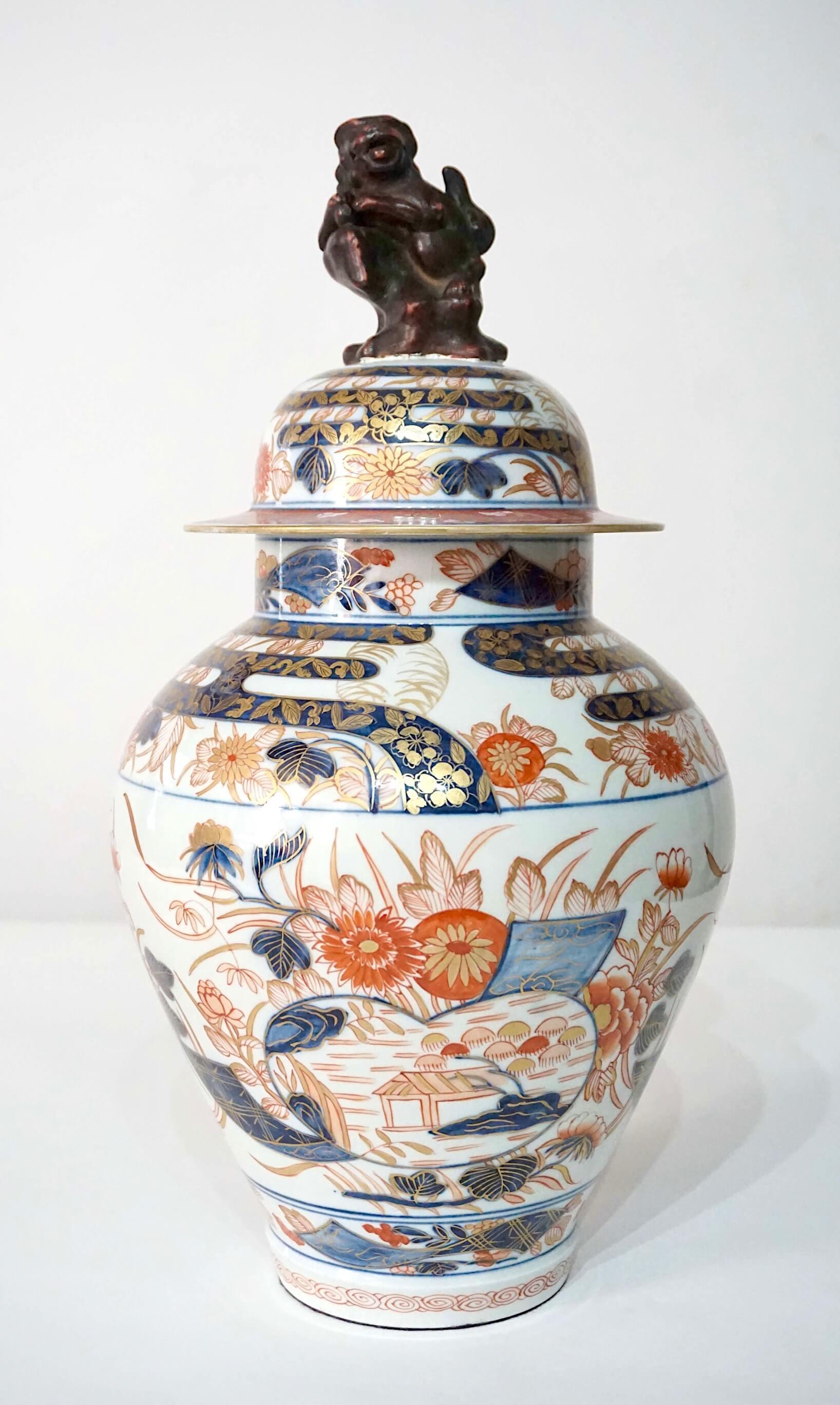 Fino jarrón de porcelana Samson del último cuarto del siglo XIX, en forma de balaustre cubierto, pintado al estilo japonés Edo Imari, con tapa original con remate de perro de caza y cuerpo de fondo blanco con decoración floral dorada y policromada