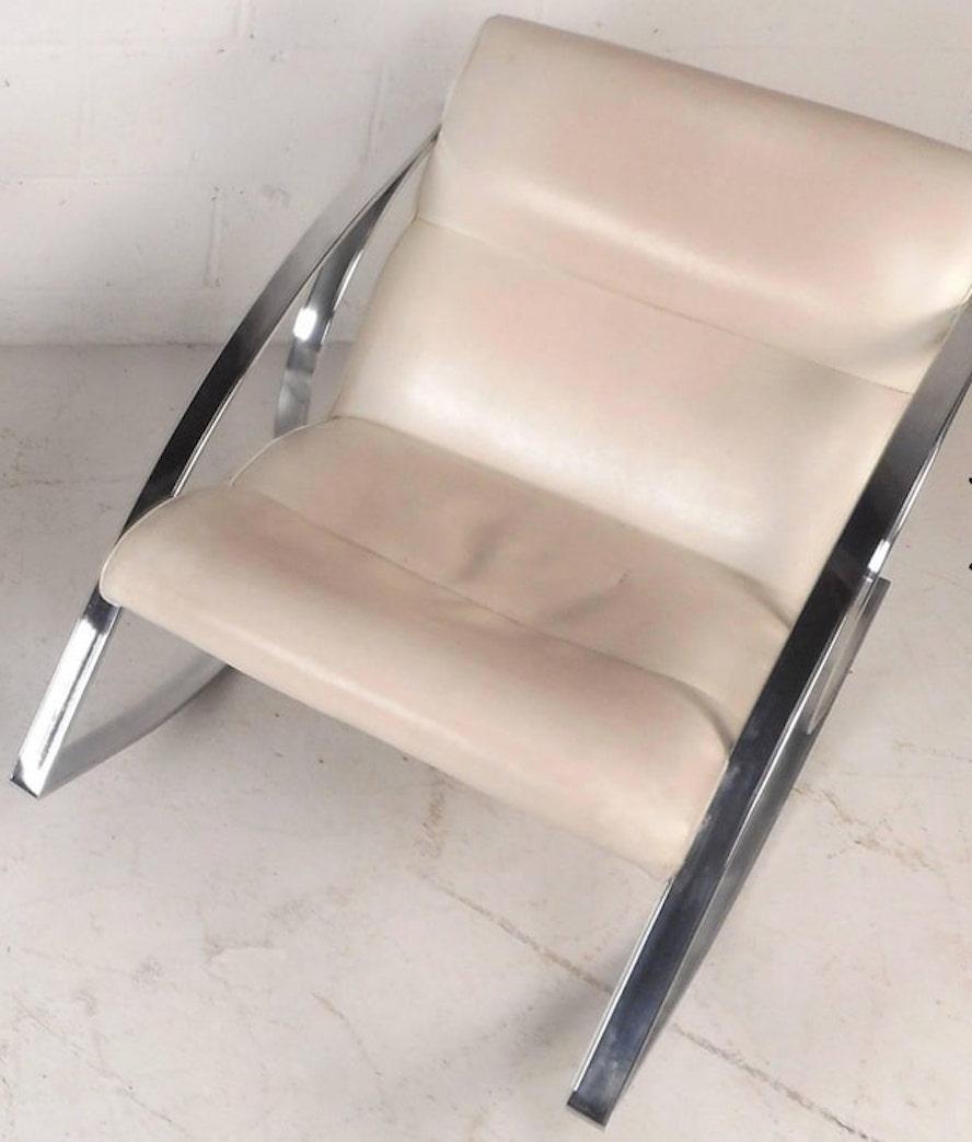 Superbe fauteuil à bascule vintage avec un cadre chromé sculpté unique. Mouvement de bascule extrêmement doux et confortable avec des coussins épais et rembourrés recouverts de vinyle blanc. Le design rétro épuré offre confort et style dans tout