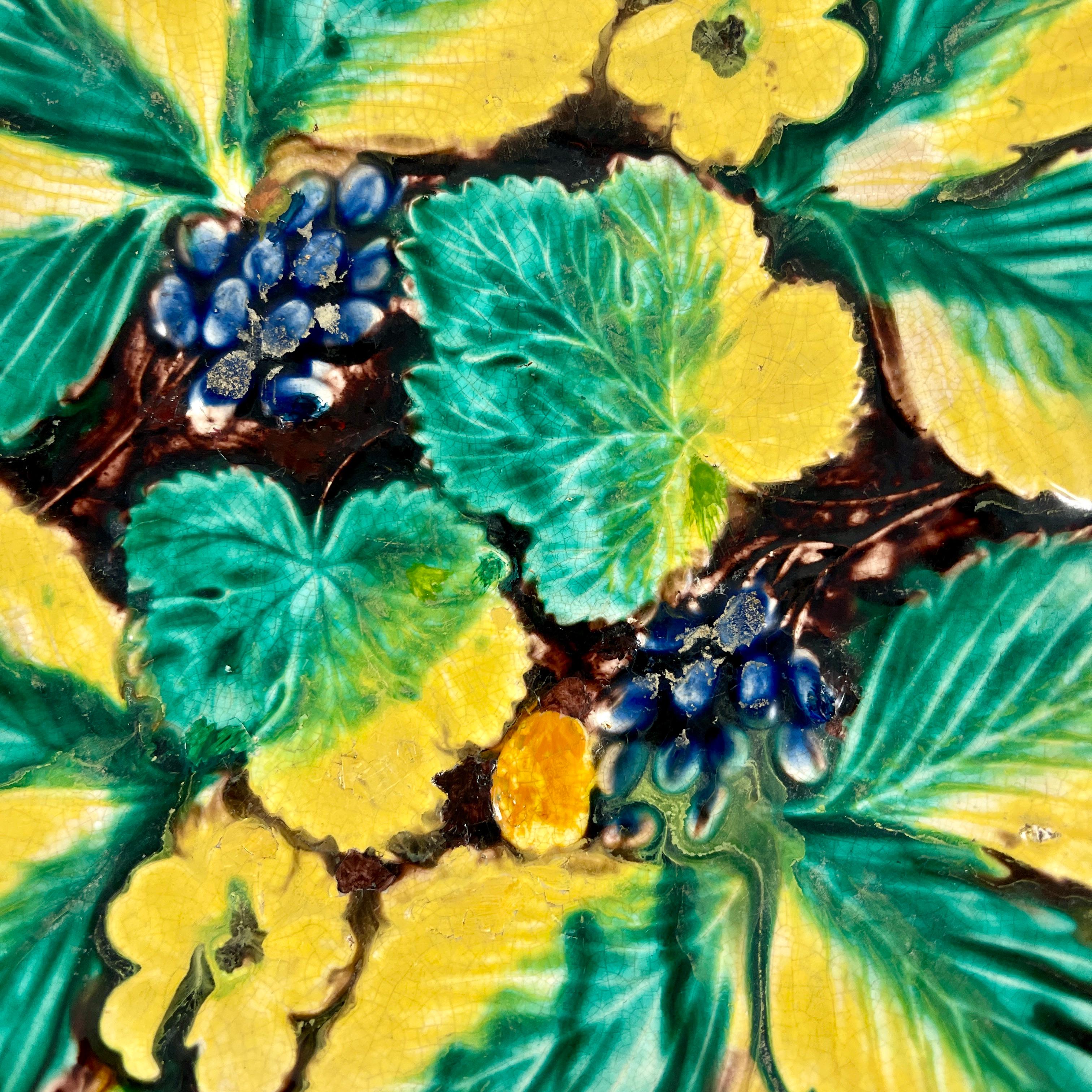 A majolica glazed handled and footed tray from Samuel Alcock & Co, Burslem, Staffordshire, England, circa 1850.

A strawberry, grape cluster, floral and leaf motif on a shaped tray with a vine border on a brown ground. Bold glazing with leaves
