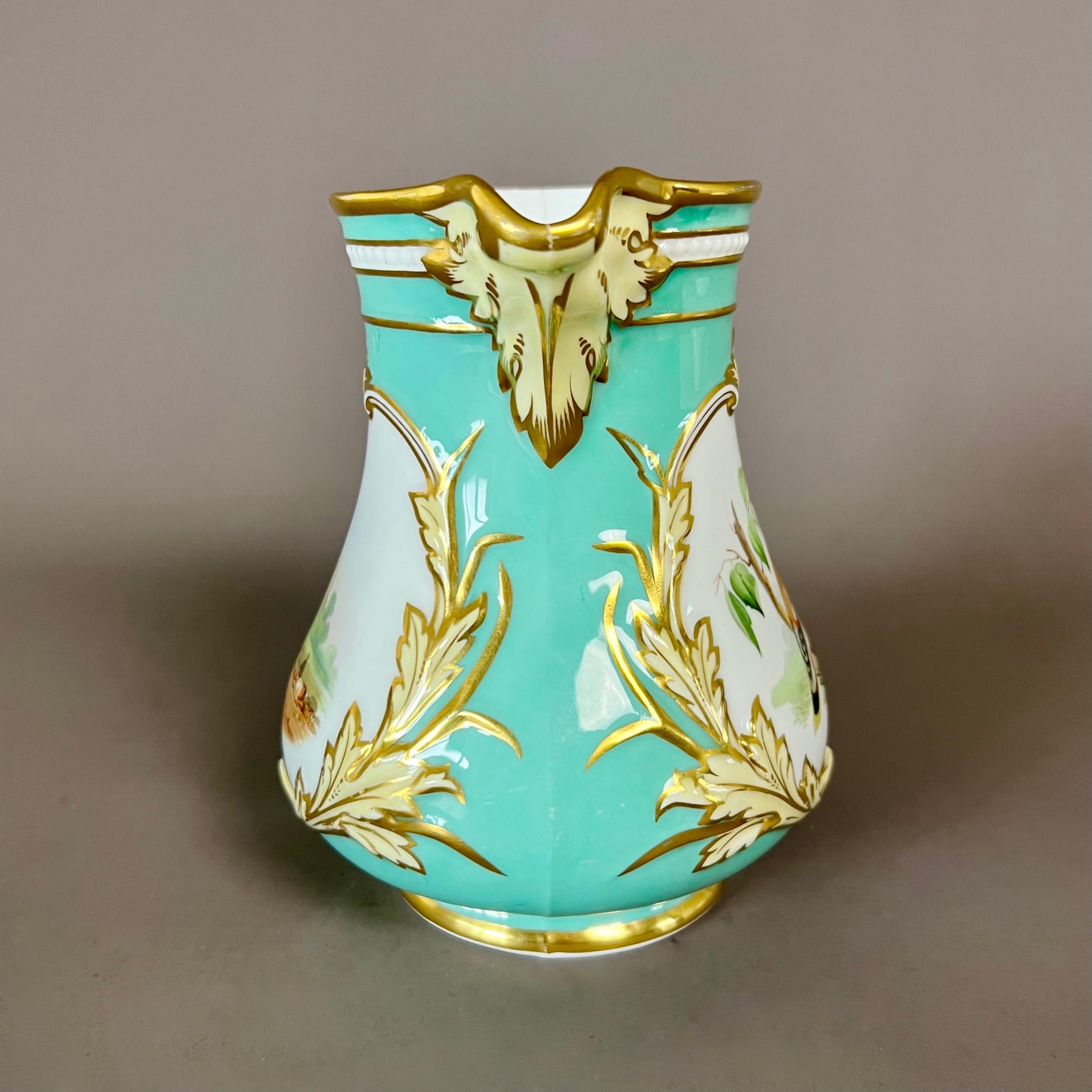 A cream or water jug / pitcher with elegant scrolled moulding, an eau de nil ground colour with yellow and gilt leafy scrolls, with a jay on one face and a landscape on the other

Pattern unknown
Year: 1854
Size: 143m (5.1”) from handle to mouth,