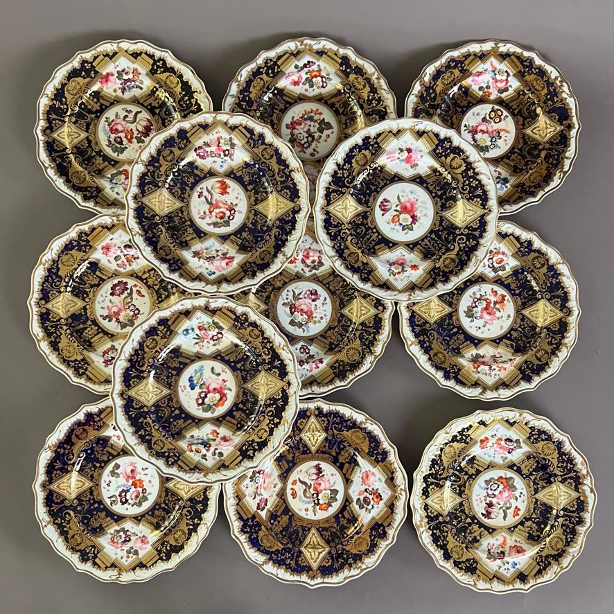Magnífico servicio de postres completo de gran tamaño, compuesto por una pieza central de pie alto, cuatro platos rectangulares, cuatro platos ovalados, tres platos de hoja, dos soperas con tapas y soportes, y doce platos. Con bordes moldeados de