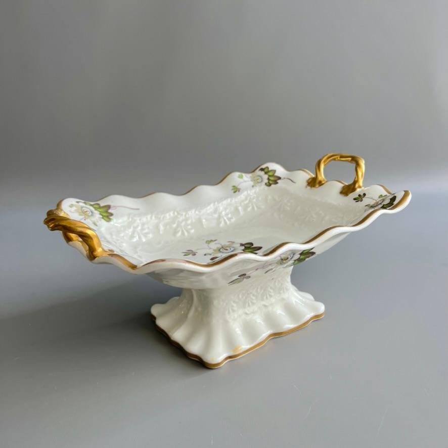 A footed rectangular central comport or centre piece, embossed shape with rope handles; white with scattered white passion flowers and gilt handles.

Pattern 1061
Year: ca 1824
Size: 34cm X 23cm (13.5” X 9”)
Condition: a complex crack in the foot