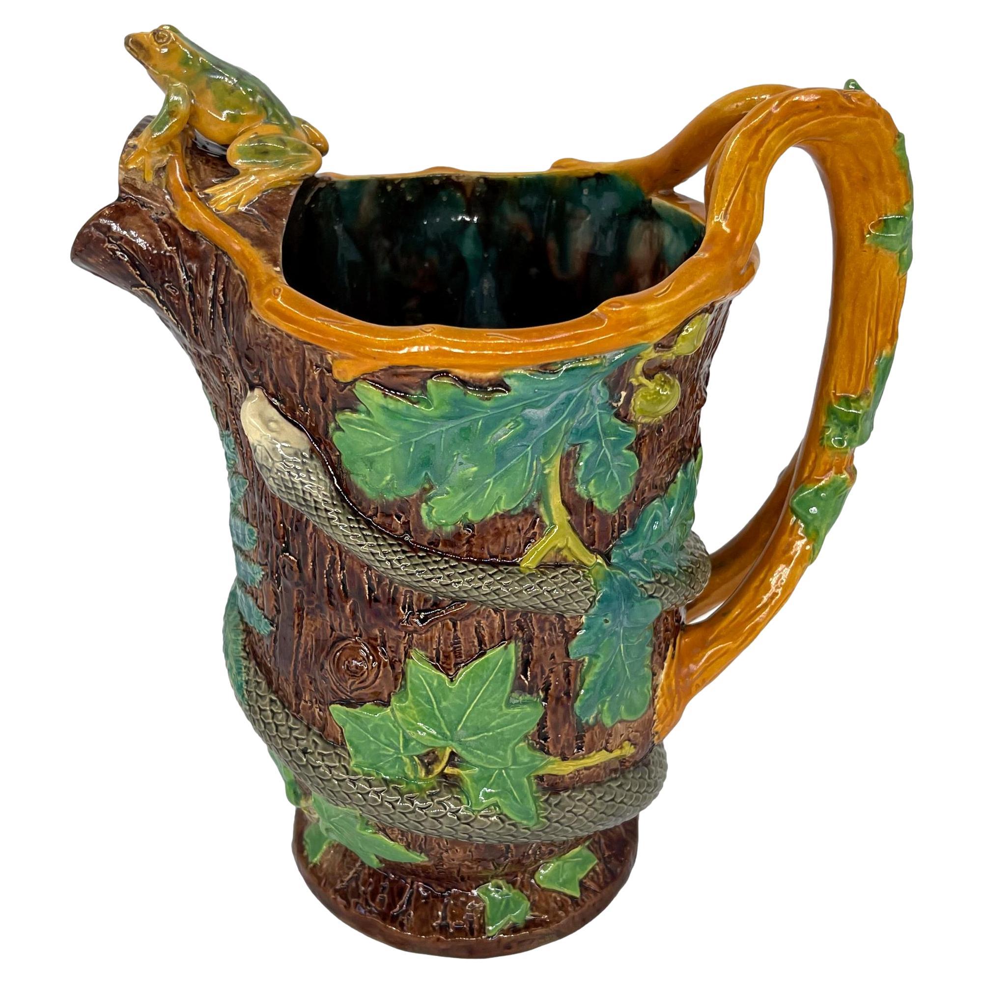 A Samuel Alcock Majolica Pitcher, the body molded as a tree trunk with ferns, oak leaves, acorns, and ivy, entwined by a high relief-molded and naturalistically glazed snake, the handle formed as crossed branches glazed in yellow ocher with