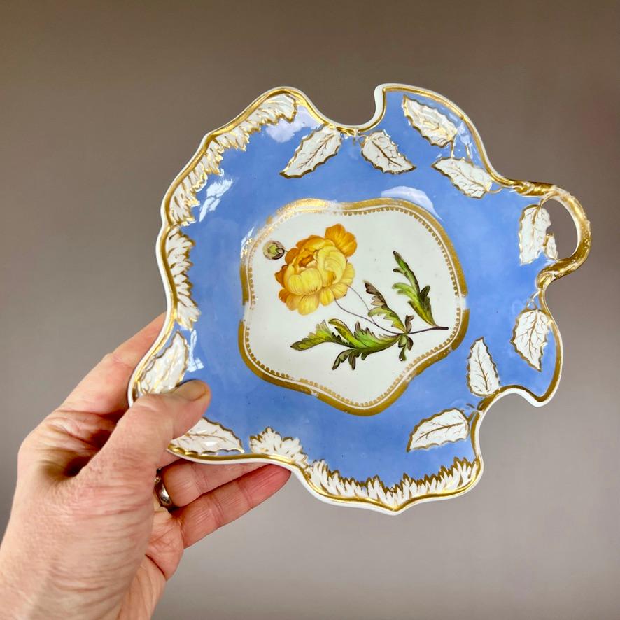A one-handled leaf dish with white melted snow and holly leaf border on a periwinkle ground, and a beautiful flower study of a yellow ranunculus in the centre

There are several other items available in near-identical style, see separate