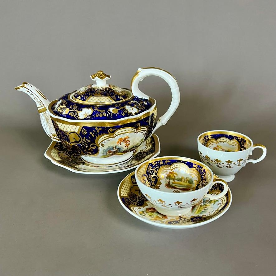 A solitaire tea set consisting of a teapot with cover on a stand and a trio consisting of a teacup, a coffee cup and a saucer, in “half orange” shape with deep cobalt blue and yellow/gilt latticed ground and very finely painted landscapes

Pattern