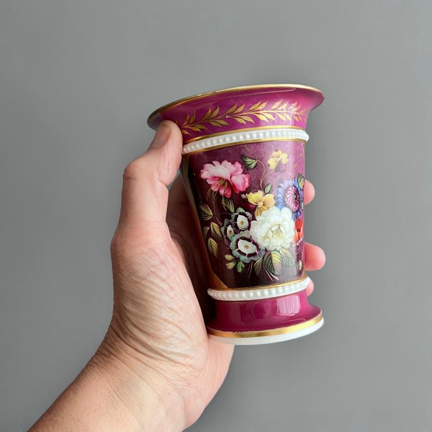 This is a beautiful spill vase with a white pearled ring around the body, a deep maroon ground and a stunning floral panel on the front, and an elegant gilt pattern on the back.

Spill vases were used to hold matches or 