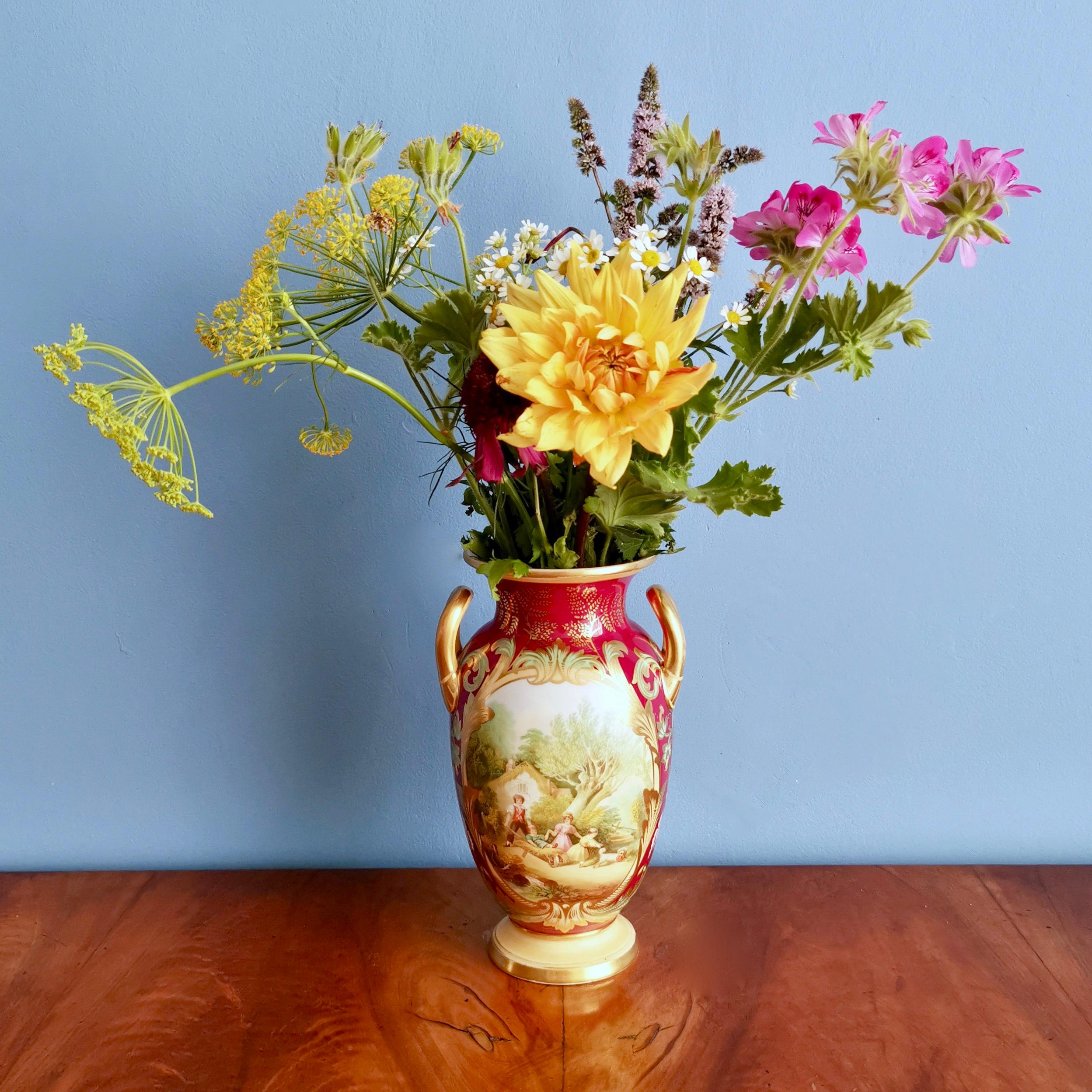 This is charming vase made by Samuel Alcock in circa 1850, which was the Victorian era. The vase has a deep maroon ground with a cheerful painting called 