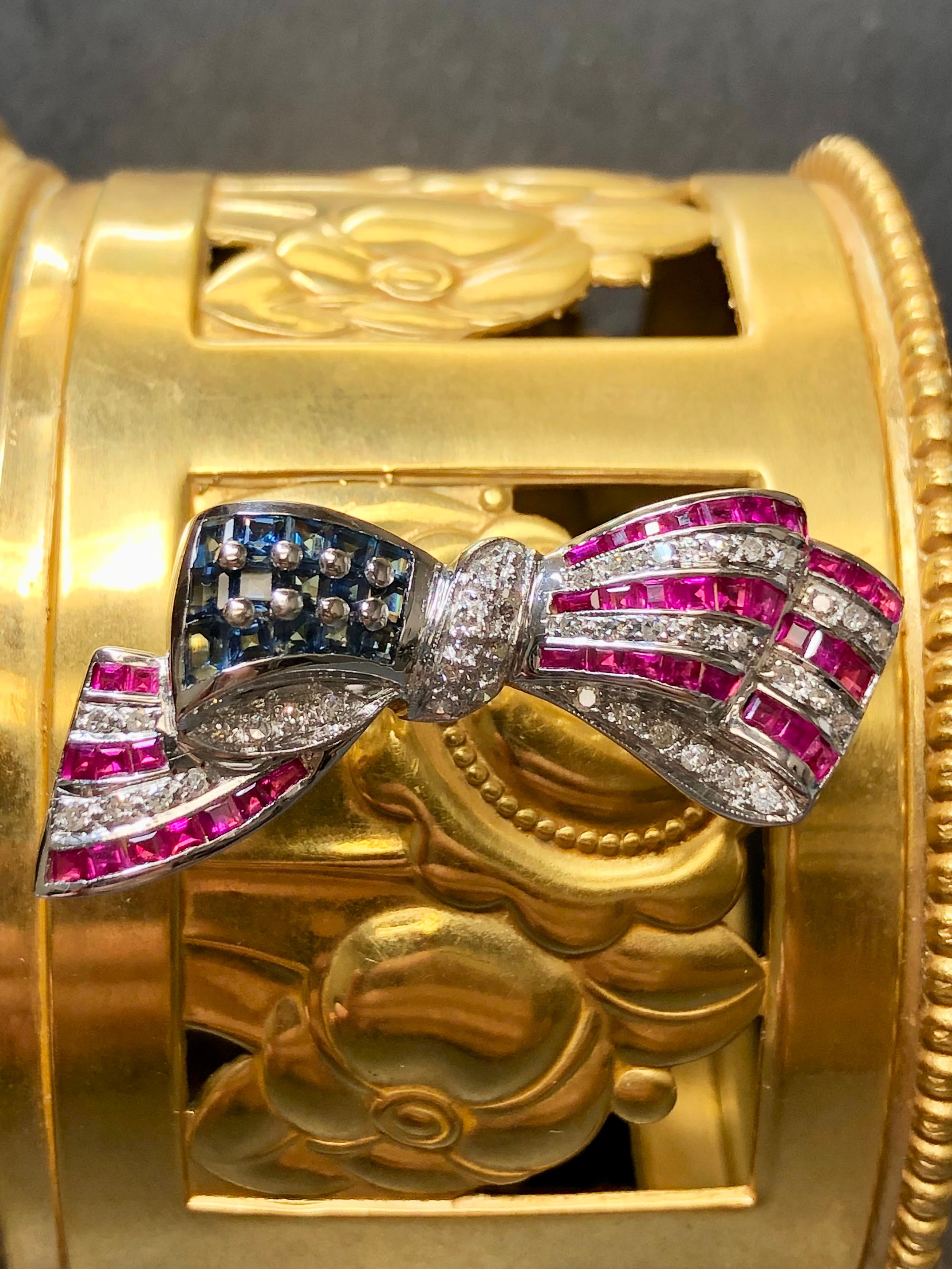 A patriotic bow pin by Samuel Benham (BJC) done in 14K white gold and set with approximately 1.60cttw in natural sapphires, 1.70cttw in natural rubies and .41cttw in H-J color Si1-2 clarity round diamonds.


Dimensions/Weight:

Pin measures 1.60” by