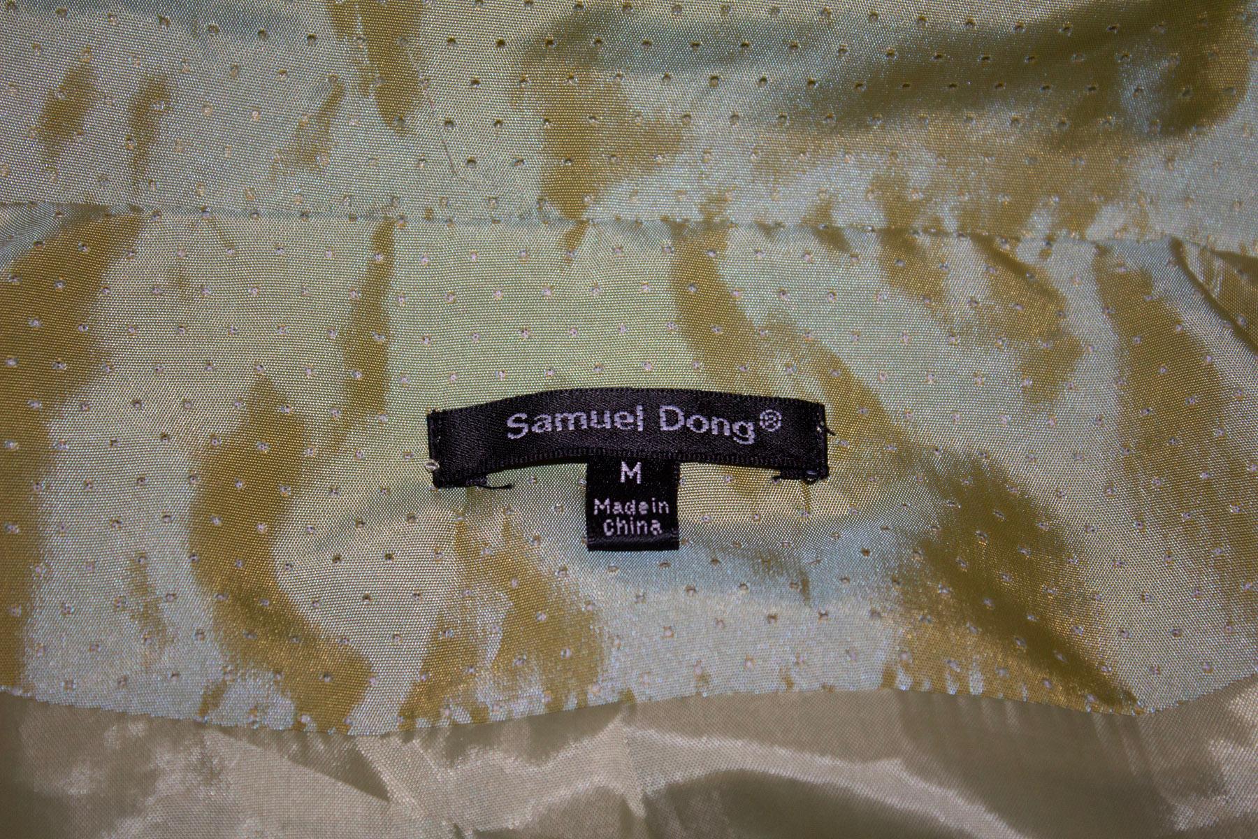 A fun shirt dress by Samuel Dong. In an attractive sage green with black spots , the dress has a button front opening, cut away collar and bubble like hem  . It has a self fabric belt , and pleat detail at the waist  and on the sleave. Size