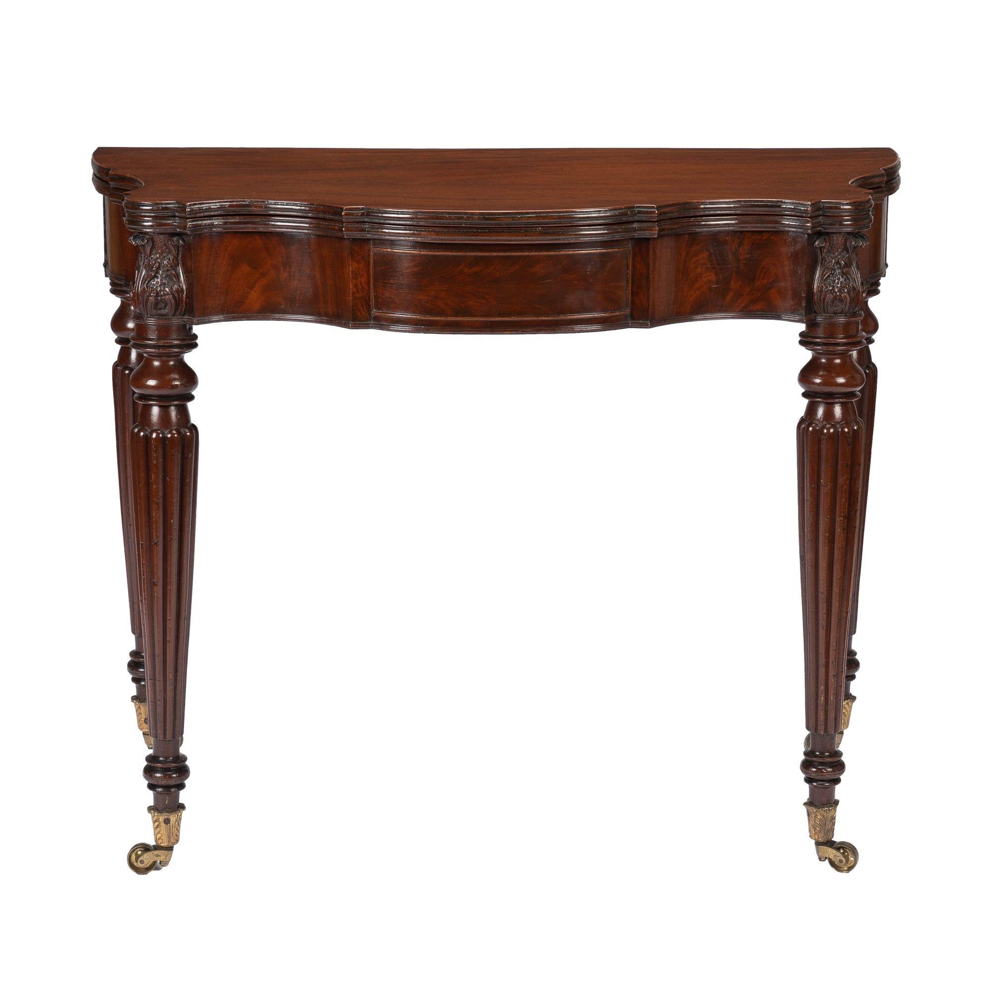 American serpentine, bull nosed, flip top mahogany game table with ovolo cut corners on turreted leg dies. Attributed to Samuel Field MacIntire, Salem, Massachusetts. The table has a conforming apron of matched figured mahogany veneers framed by