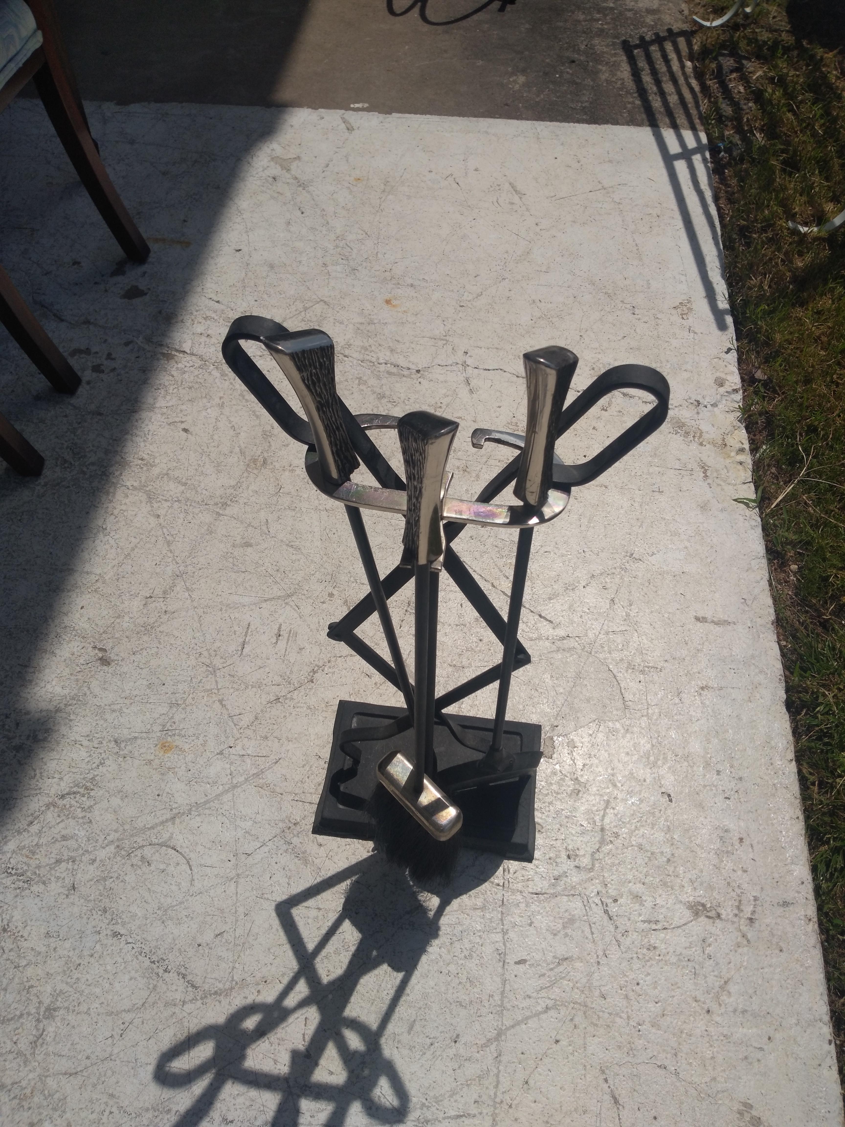 This is a nice fireplace poker set. It's rendered in the style of Samuel Marx. It has nickel handles and brush cover. The harness is nickel and the irons and base are black colored metal.