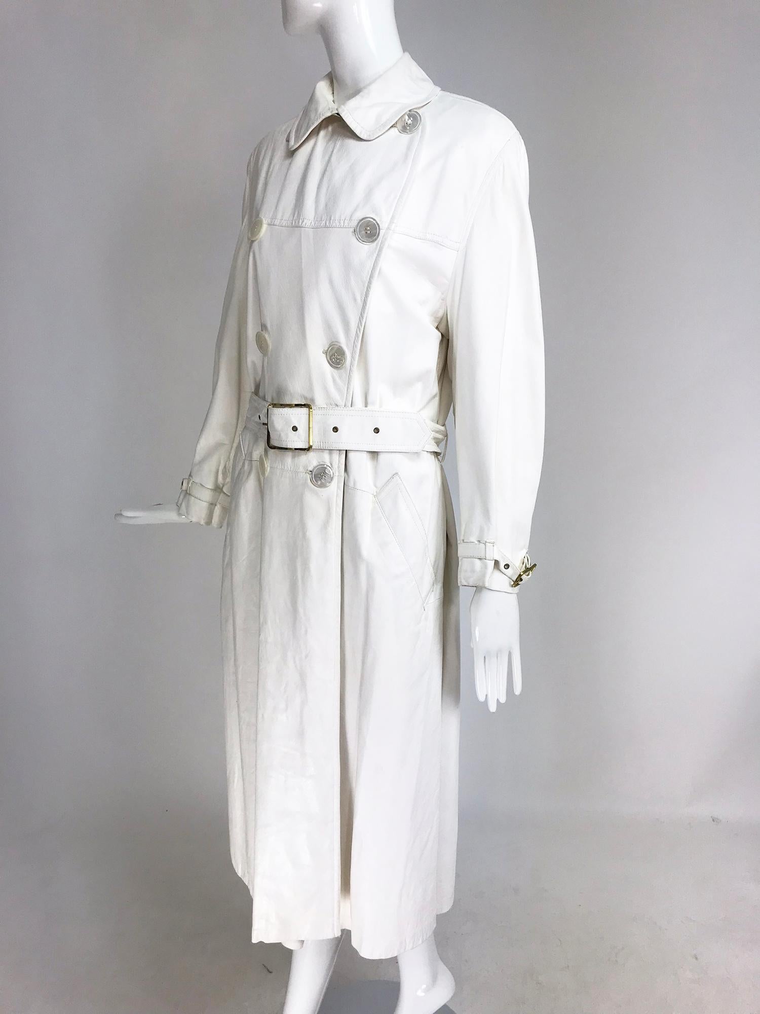 Samuel Robert white soft leather trench coat from the 1960s. Beautiful and soft white leather trench coat closes at the front with mother of pearl buttons, the leather belt and wrist belts close with narrow gold buckles. Front angled hip pockets.