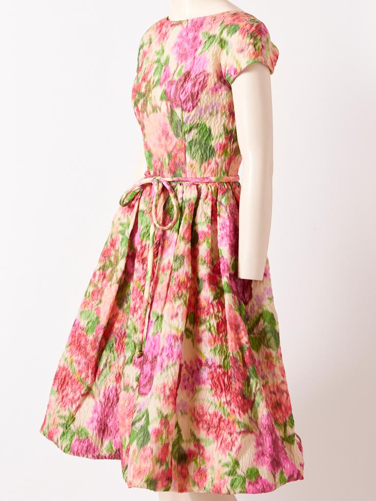Samuel Winston, crinkled silk, impressionistic, soft tones, floral pattern, dress having a bateau neckline, cap sleeve, fitted bodice, and full gathered skirt. Tubular self belt ties at the waist. C. 1960's.