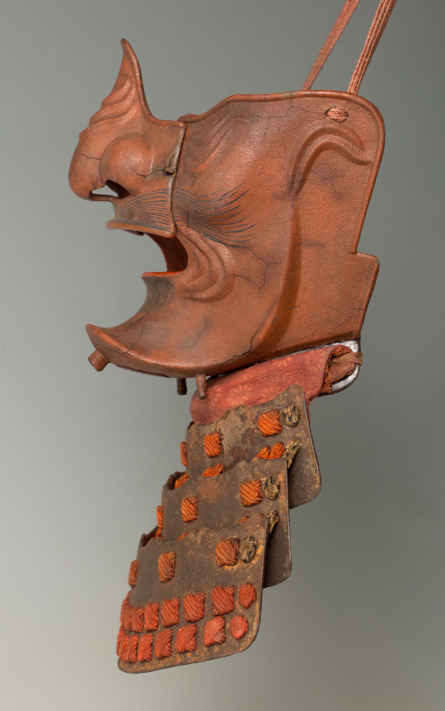 Samurai mask with a fierce expression
Ressei Menpo

DATE Edo period (1615 - 1867), 18th century
 

A red lacquered high-level mask, with fierce (ressei) expression finely embossed with wrinkles all over the face. The expression is emphasized