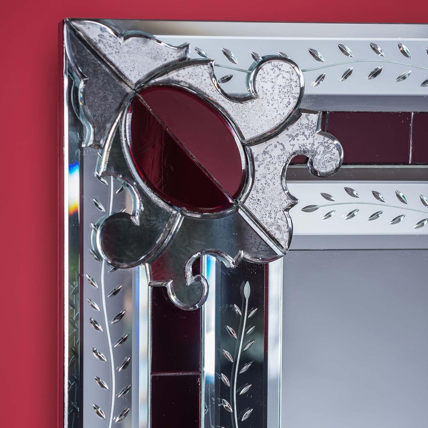 Magnificent rectangular mirror composed of beveled and silvered mirror embroideries in the corners, all handmade with bands engraved with a floral subject, on a red Murano glass mirror background. This miniature reproduction of a larger mirror is