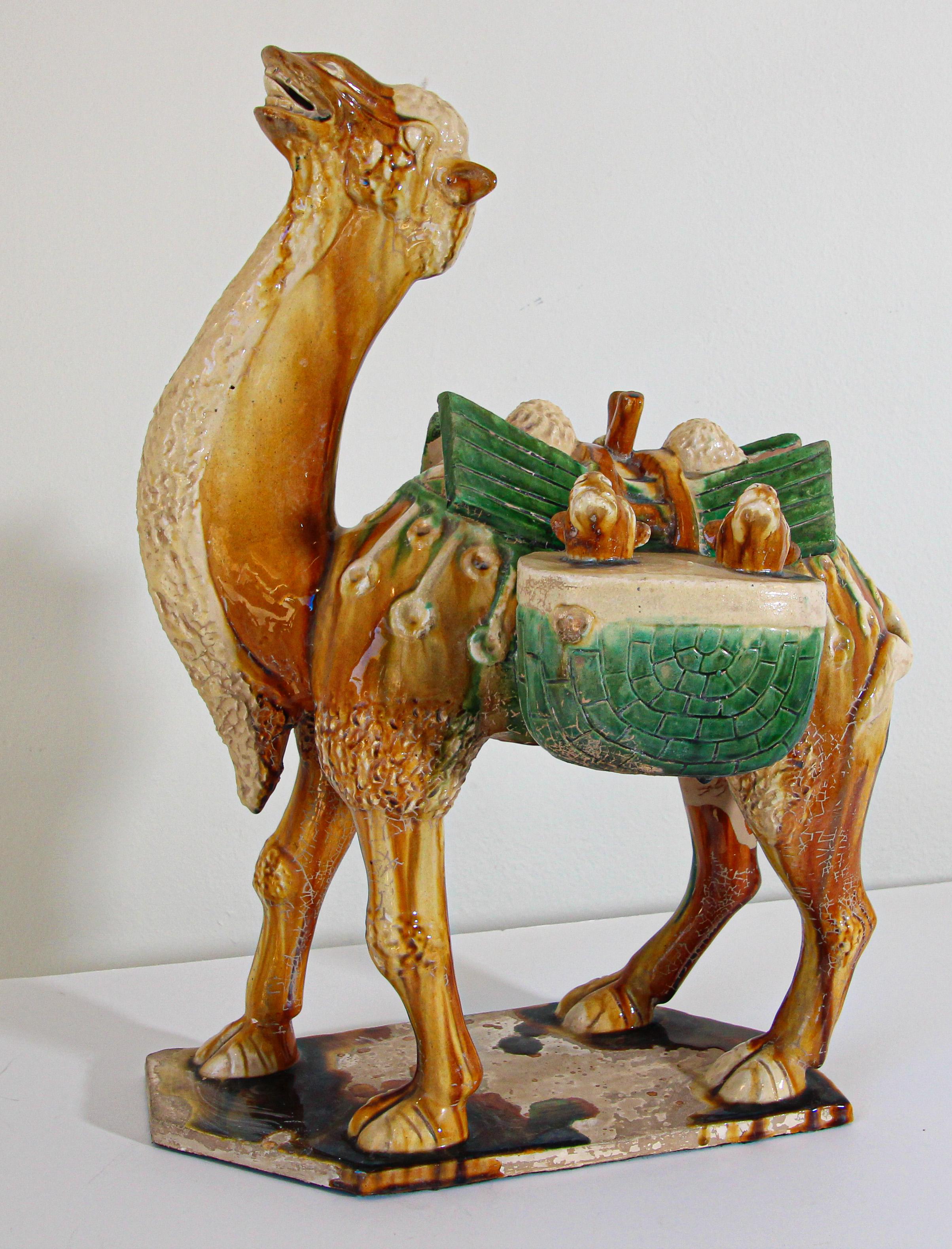 Vintage Sancai glazed blue pottery figure of a camel Chinese Tang Dynasty manner.
A wonderful large Chinese Tang-style glazed pottery figure of a camel carrying goods.
Made from traditional glazed ceramic in glossy orange and green, glazed and