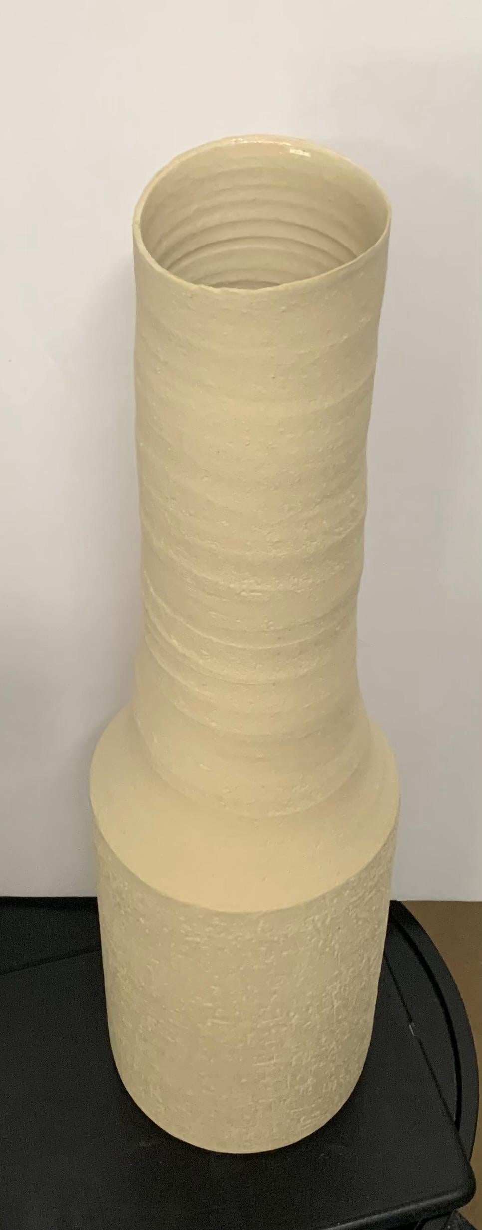 Contemporary German handmade stoneware vase.
Tall, thin funnel neck opening.
Sand color stoneware.
Part of a large collection of handmade vases of different sizes , shapes and textures