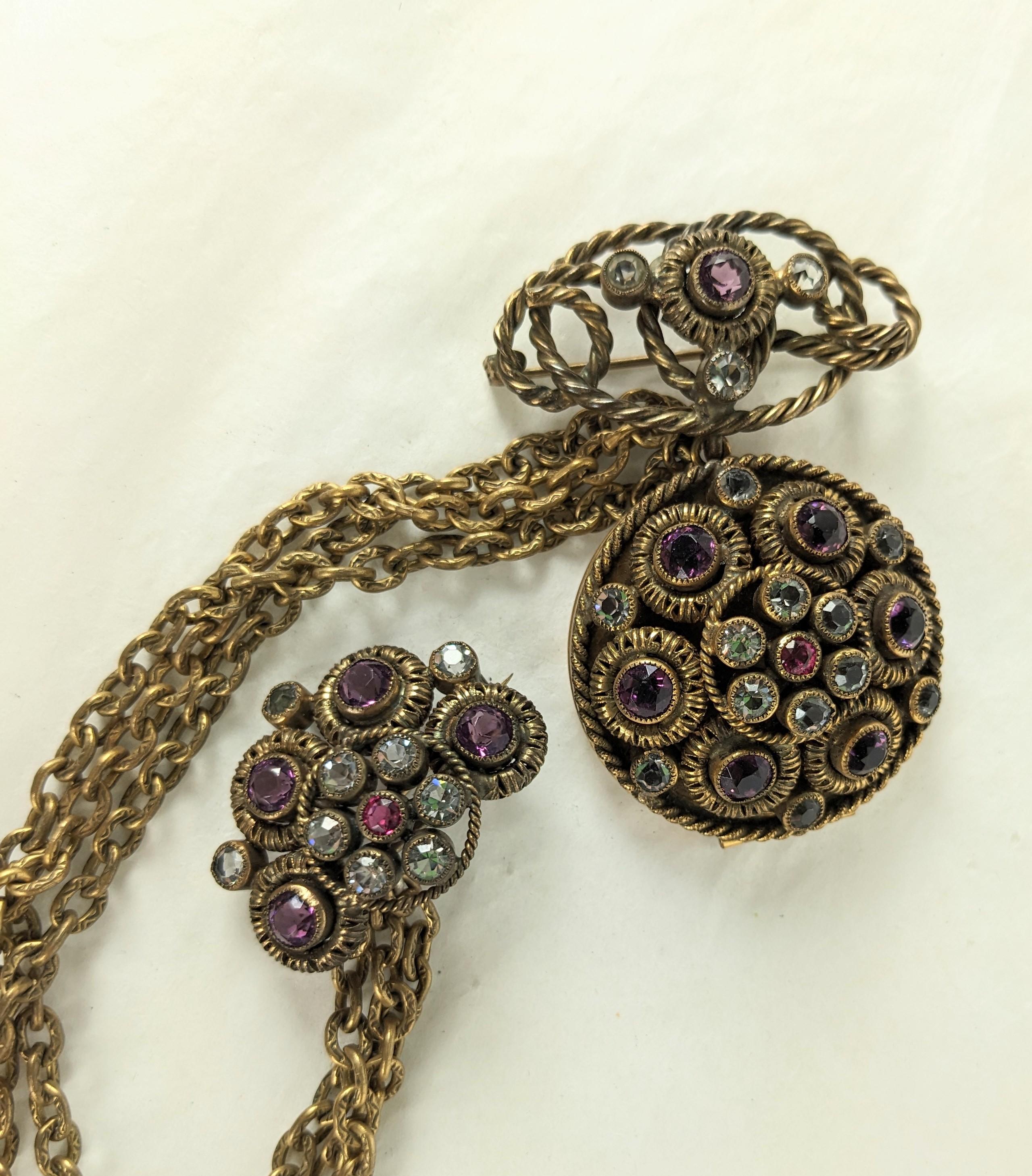Unusual Sandor Jeweled Locket Chatelaine Brooch from the 1940's. Set in antique bronze finish with paste set locket in crystal, purple and ruby with swag chaining. 1940's USA. Locket brooch 2.5
