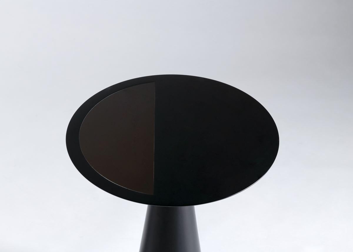 This one of a set of nesting occasional tables, made of a silky smooth, laminated Corian, plays with the contrast of night with day, of light with darkness. The pieces are entirely black and white and adorned with intricate, laser cut and bronze