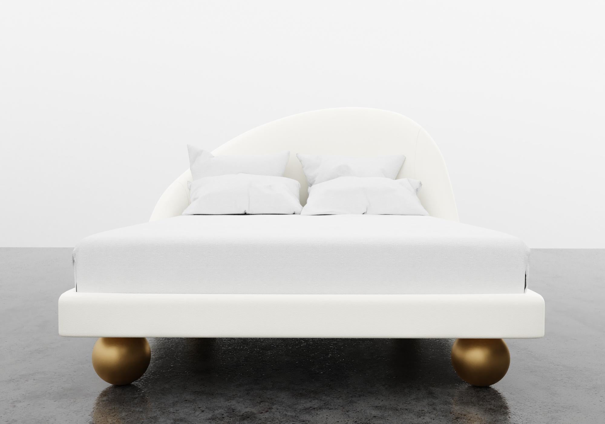The Sandrine bed features a modern asymmetrical upholstered headboard and an upholstered platform base with round metal legs. COM will be used for fabric with Polished Bronze legs. CAD will be drawn to outline dimensions and receive customer