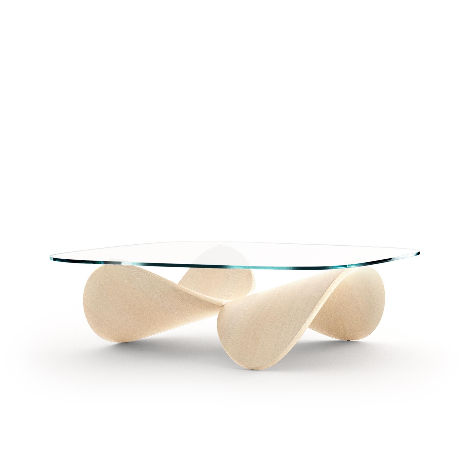 A coffee table that is both furniture and sculpture designed for authentic living spaces. Two identical wooden shells are arranged together in a reversed posture and are joined to create a sculptural structure for the glass top. 
The table was named