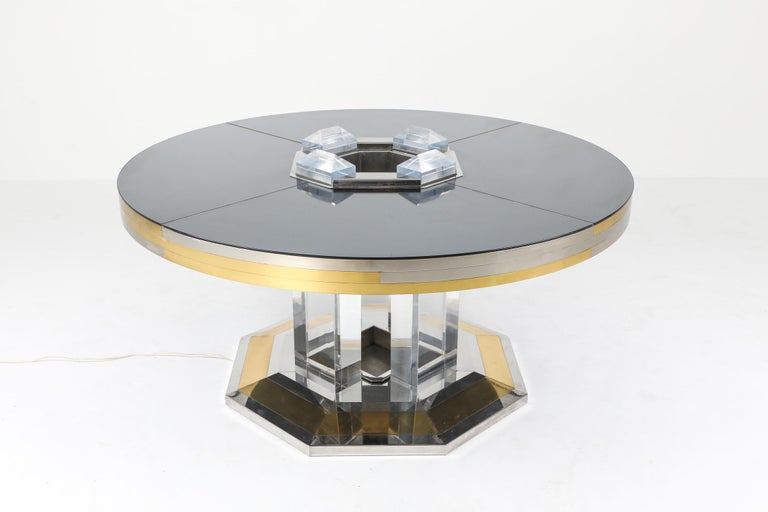 Metropolitan chic round dining table by Sandro Petti for l'angelometallarte, Italy, 1970s.
High-end piece that fits well in a Hollywood regency decor.
From a brass and chrome octagonal base, four huge Lucite column rise to hold the impressive