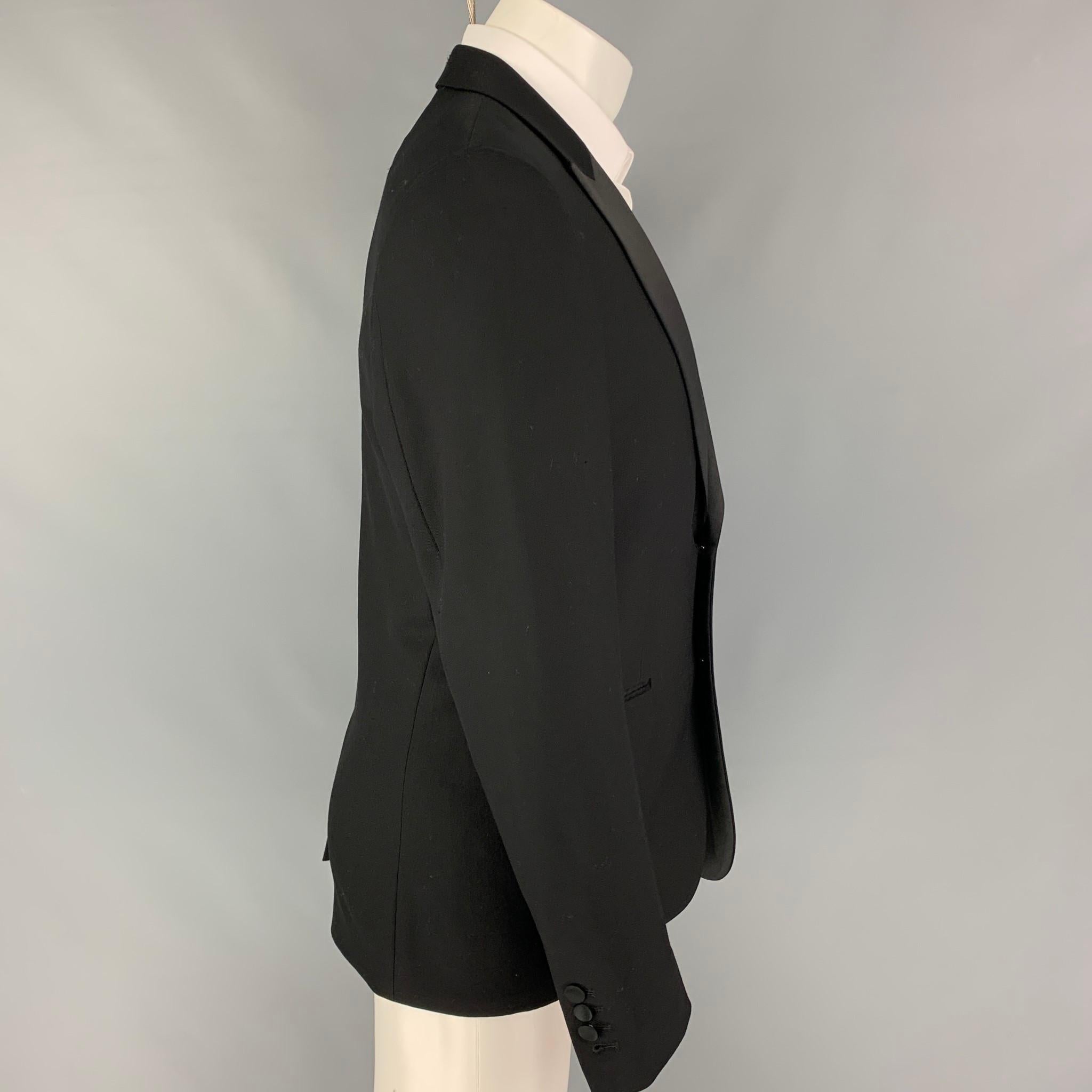 SANDRO sport coat comes in a black wool with a full liner featuring a peak lapel, slit pockets, single back vent, and a double button closure. 

Very Good Pre-Owned Condition. Light mark at logo tag.
Marked: 50

Measurements:

Shoulder: 17.5