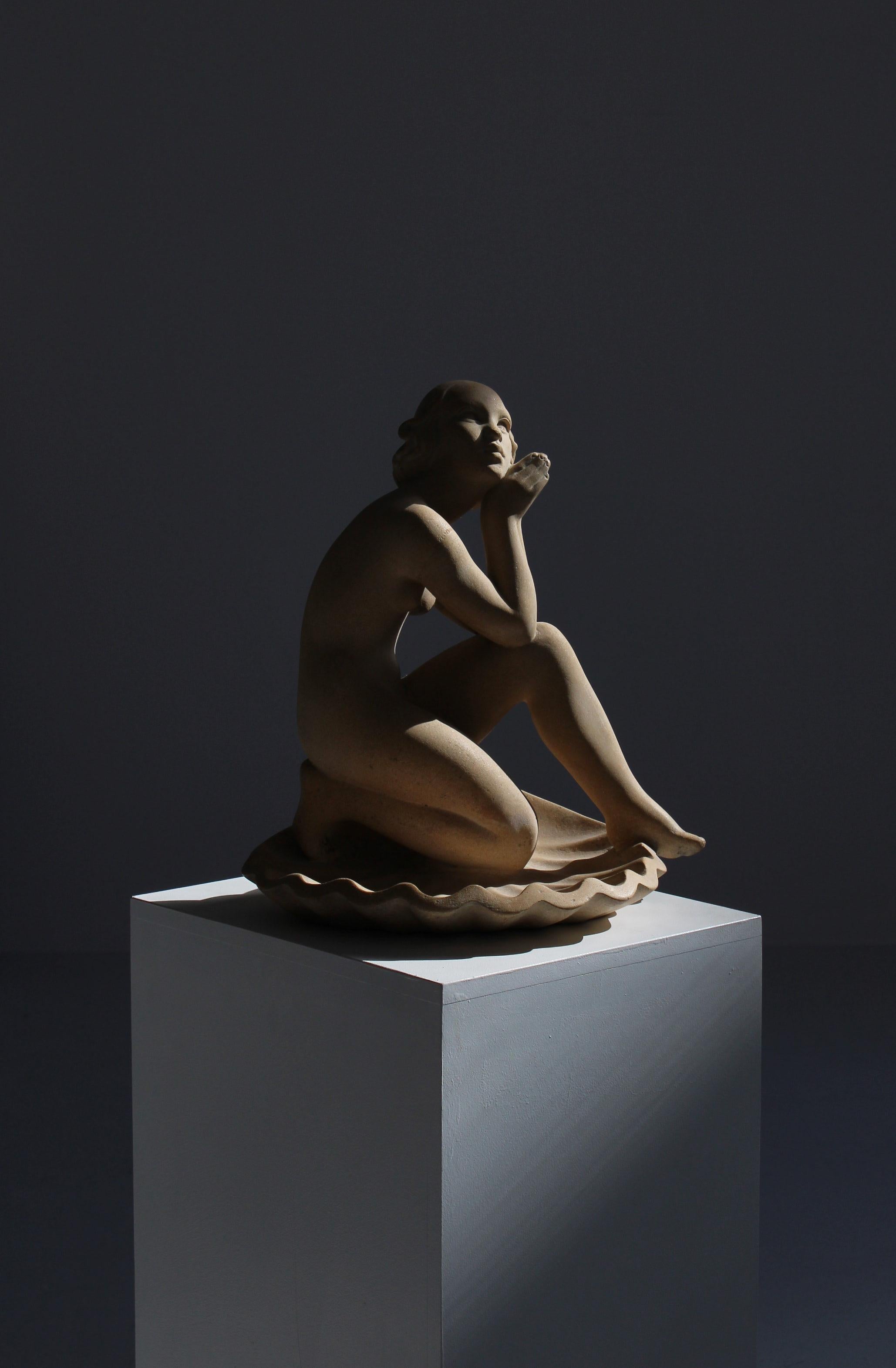 Große schöne figurative Skulptur des dänischen Künstlers Jens Jacob Bregnø im Jugendstil. Die Skulptur ist aus rohem Sandstein gefertigt und vom Künstler signiert. Es zeigt eine weibliche Figur, die auf einer Jakobsmuschel sitzt -