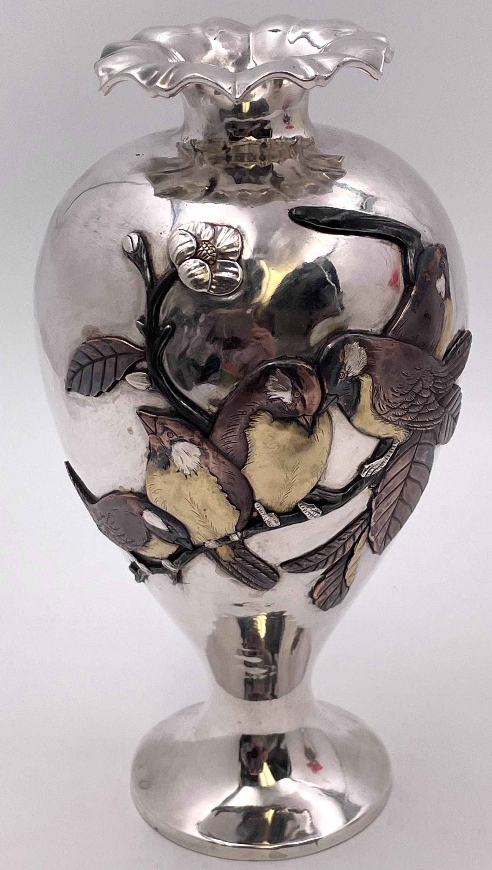 Exquisite pair of Japanese sterling silver vases, by Sanju Saku, with exquisite, applied metal motifs showing birds on branches and flowers, from the late 19th or early 20th century. They measure 10'' in height by 3'' in diameter at the top.