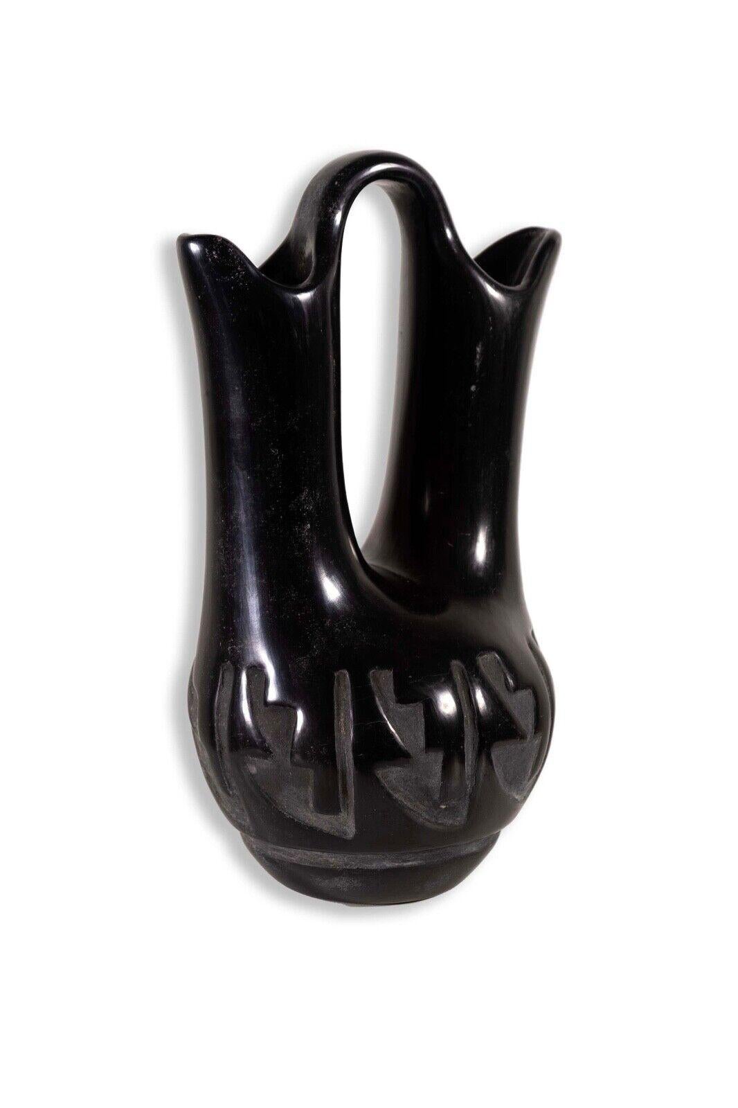 An exquisitely carved Santa Clara Pueblo blackware pottery by Southwest Native Legoria Tafoya. Etched signature on bottom of the sculpture. An iconic example of pueblo pottery with a rounded base with two spouts. Polished to showcase a high gloss