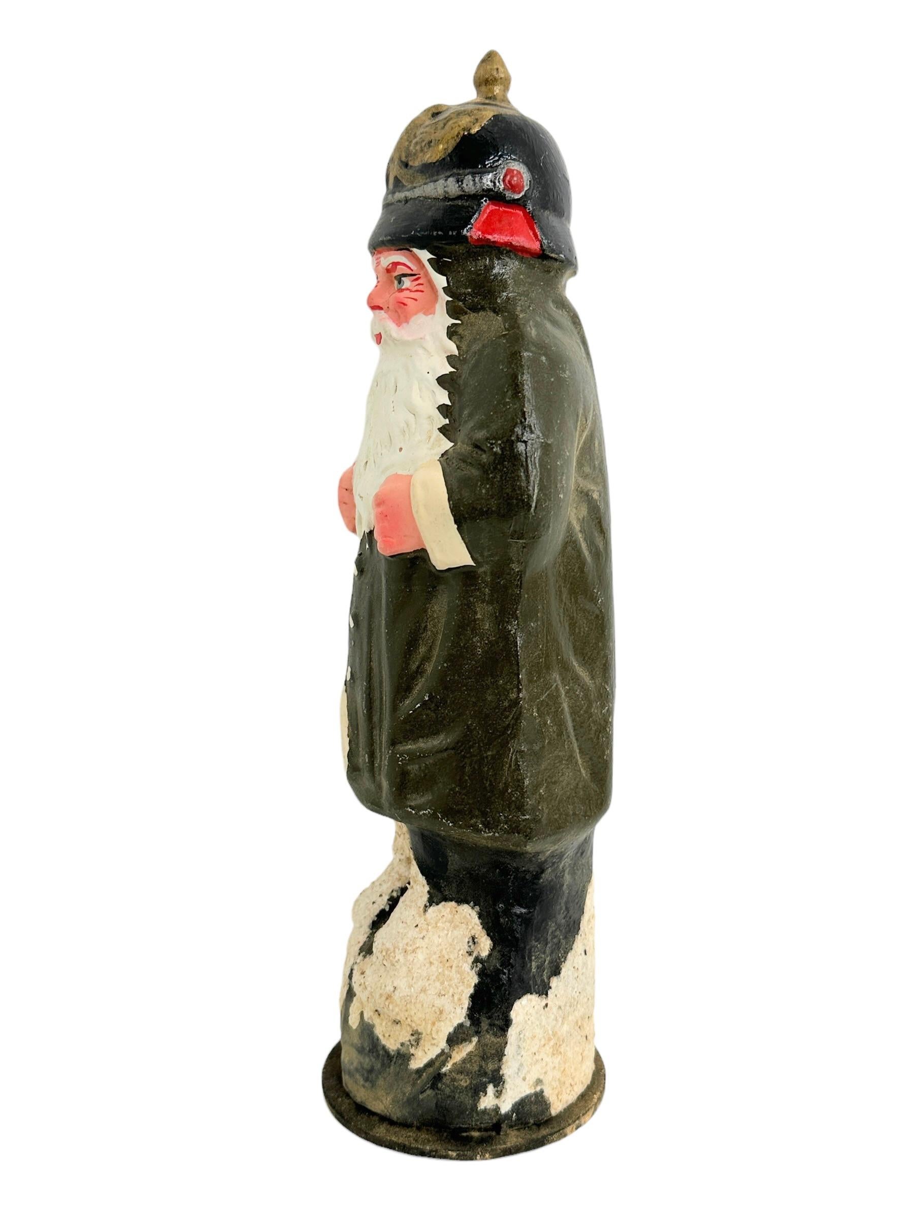 A beautiful German Belsnickle / Santa Claus candy container. Was probably made before World War One in Germany. We attribute this to the fact that he is wearing a spiked helmet. Scattered wear due to age. It is made of paper mâché, Cardboard. Nice