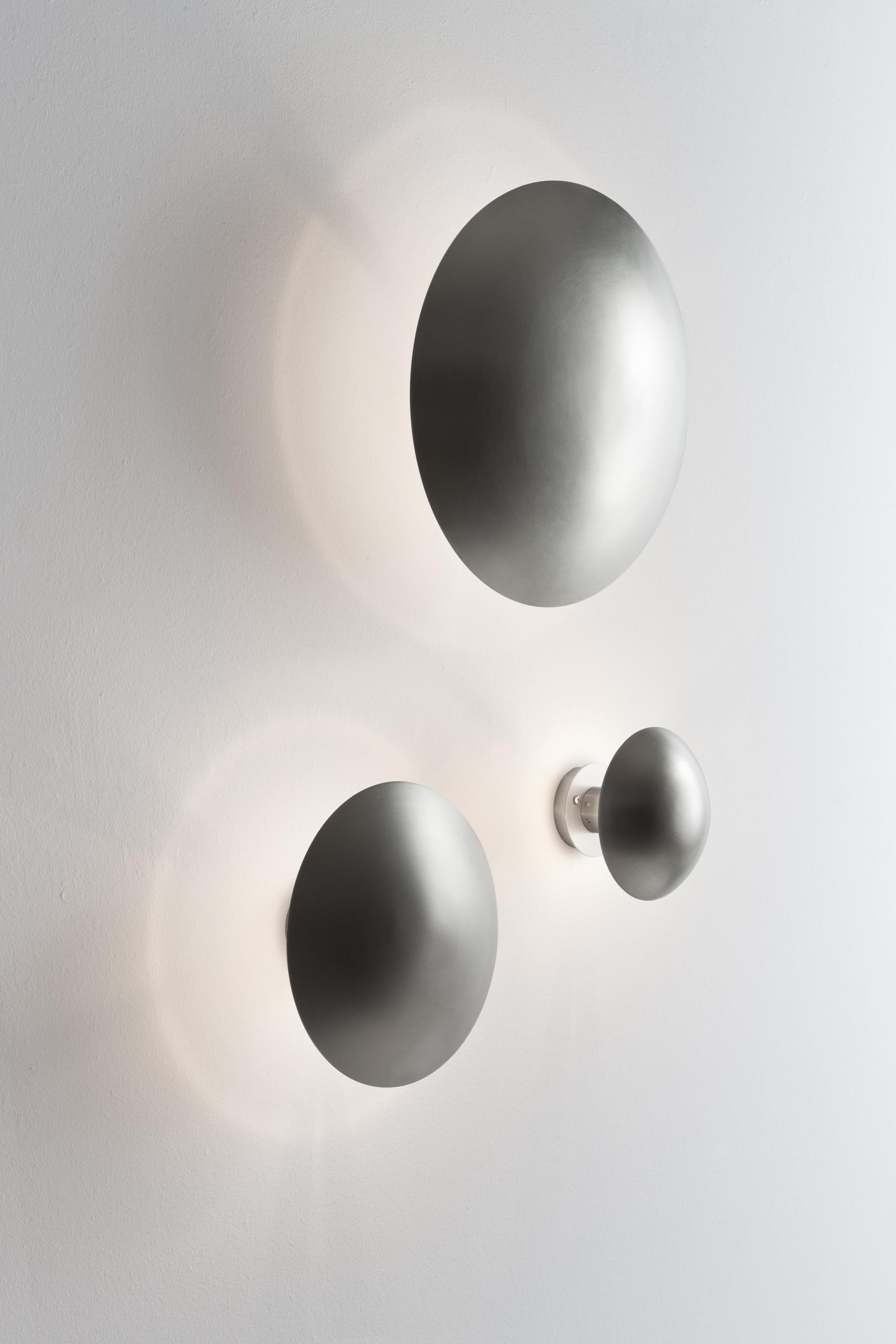 Design by Jordi Mirabell and Mariona Raventos, 1995.

A disc of molded steel which hides the source of light, giving off a glow around its opaque circle. Available in small.

Measure: Small 6