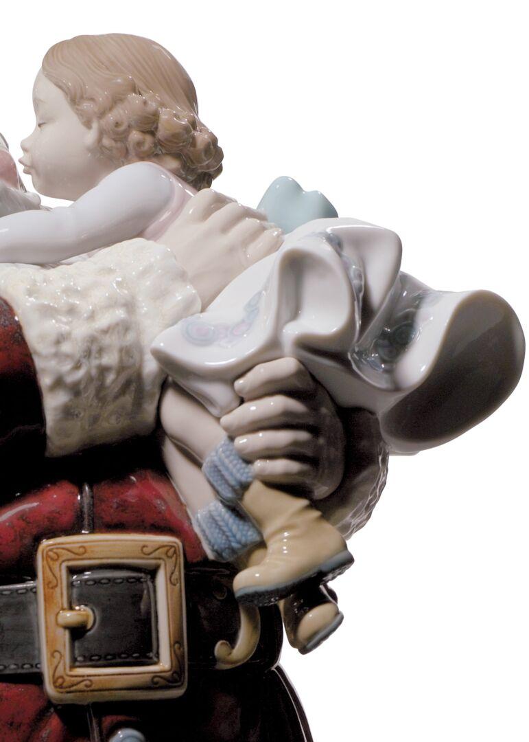 Santa Claus limited edition porcelain figurine with a sweet little girl in his arms kissing him decorated with red enamels on Santa's costume.