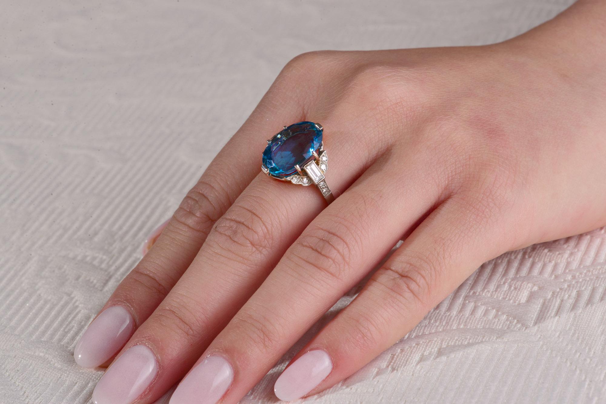 This Contemporary ring with a stunning ocean blue Santa Maria Africana Aquamarine of 7.47cts is set in a hand made Platinum mount with two Baguette Diamonds with a total weight of 0.35cts and twelve single cut Diamonds with a total weight of 0.15