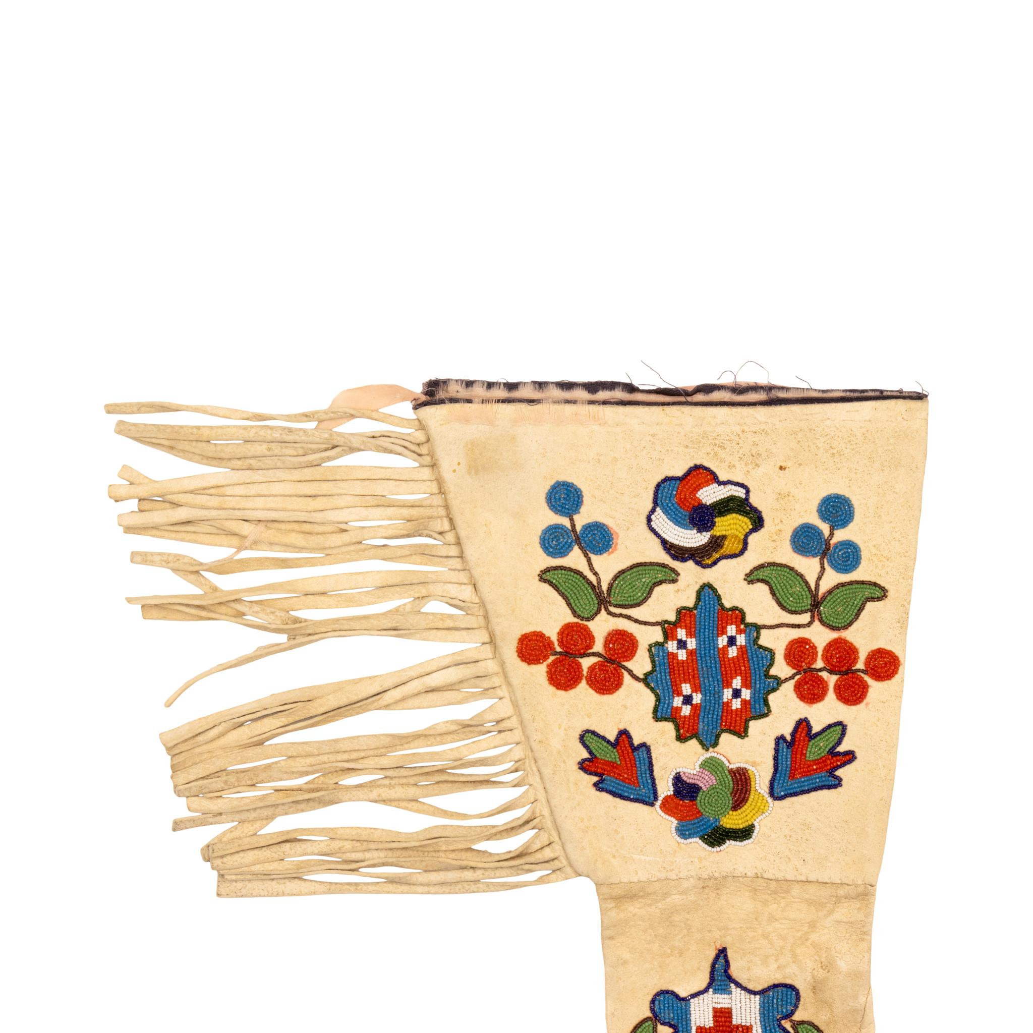 Guanteletes de cuentas de los indios americanos Santee Sioux. Llamativos guanteletes de colores con flecos laterales y abalorios clásicos en el puño, la mano y los dedos. El diseño presenta intrincados motivos florales en los puños y una cresta en