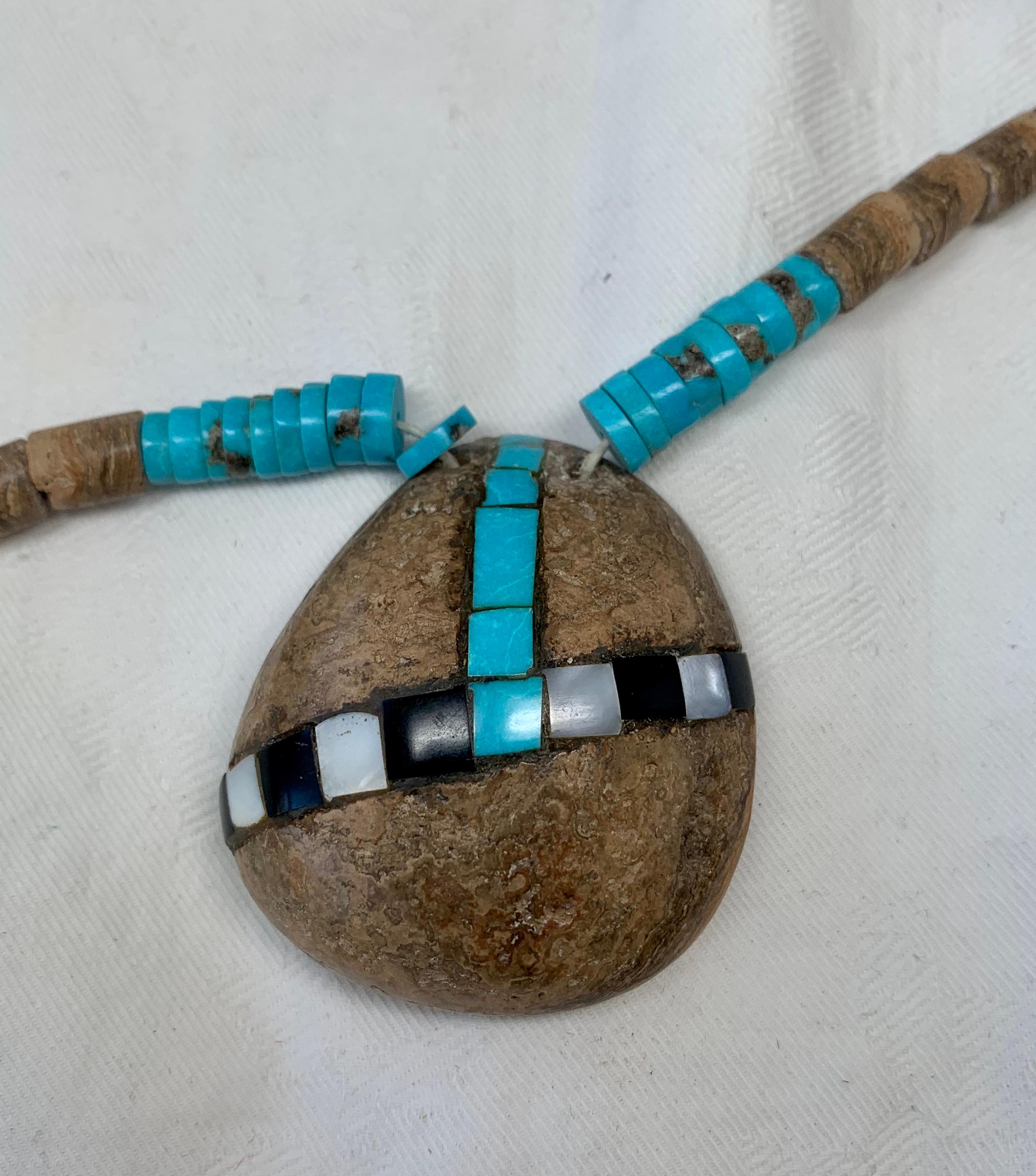 This is a fantastic, antique SANTO DOMINGO Kewa Pueblo necklace.  The piece is very rare and special as it is made with a Petrified Shell pendant instead of the typical shell. This piece consists of a large petrified shell pendant which is inlaid