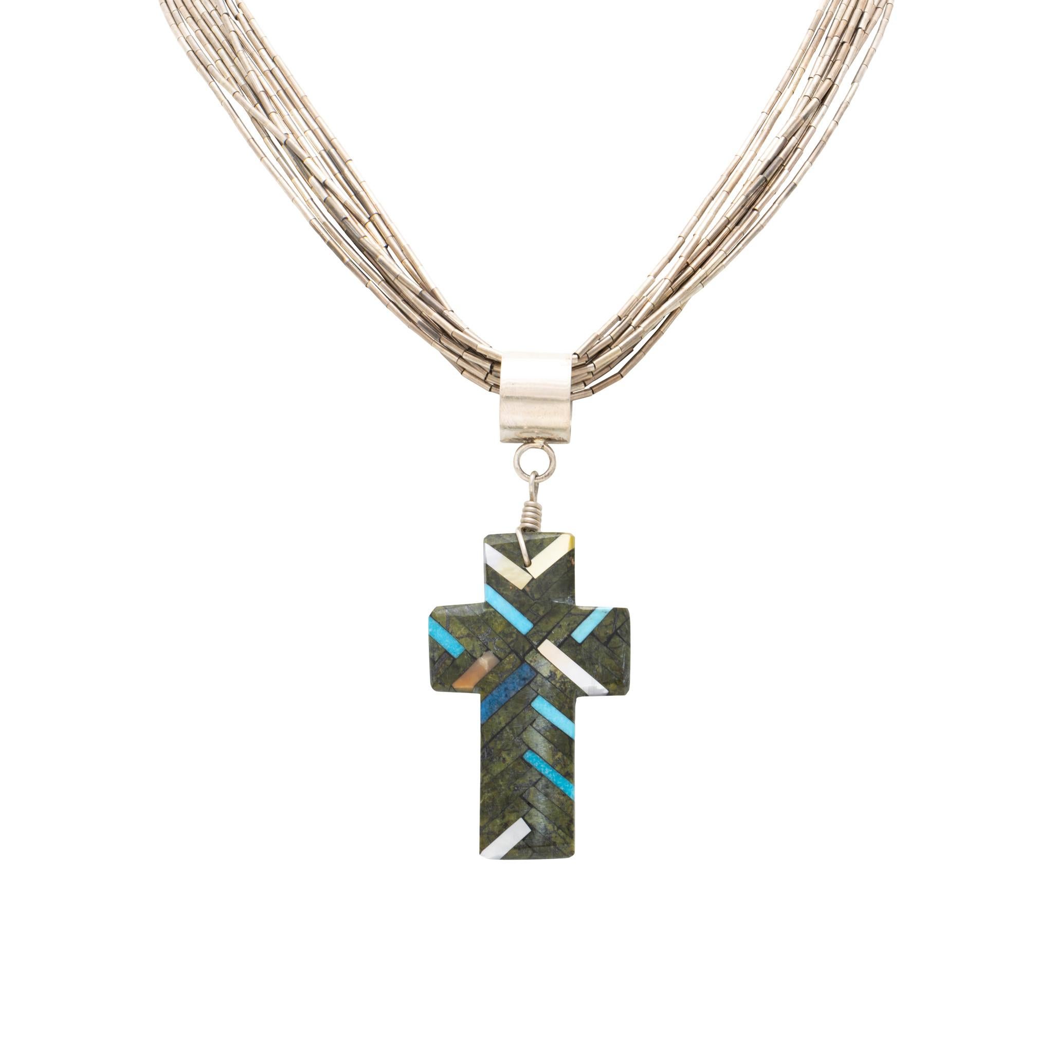 Native American Santo Domingo Indian turquoise and shell cross pendant. Pendant features a variety of stones including turquoise, mother of pearl, and more. Stones are inlaid in a herringbone pattern in a short, sleek design. Has large loop to