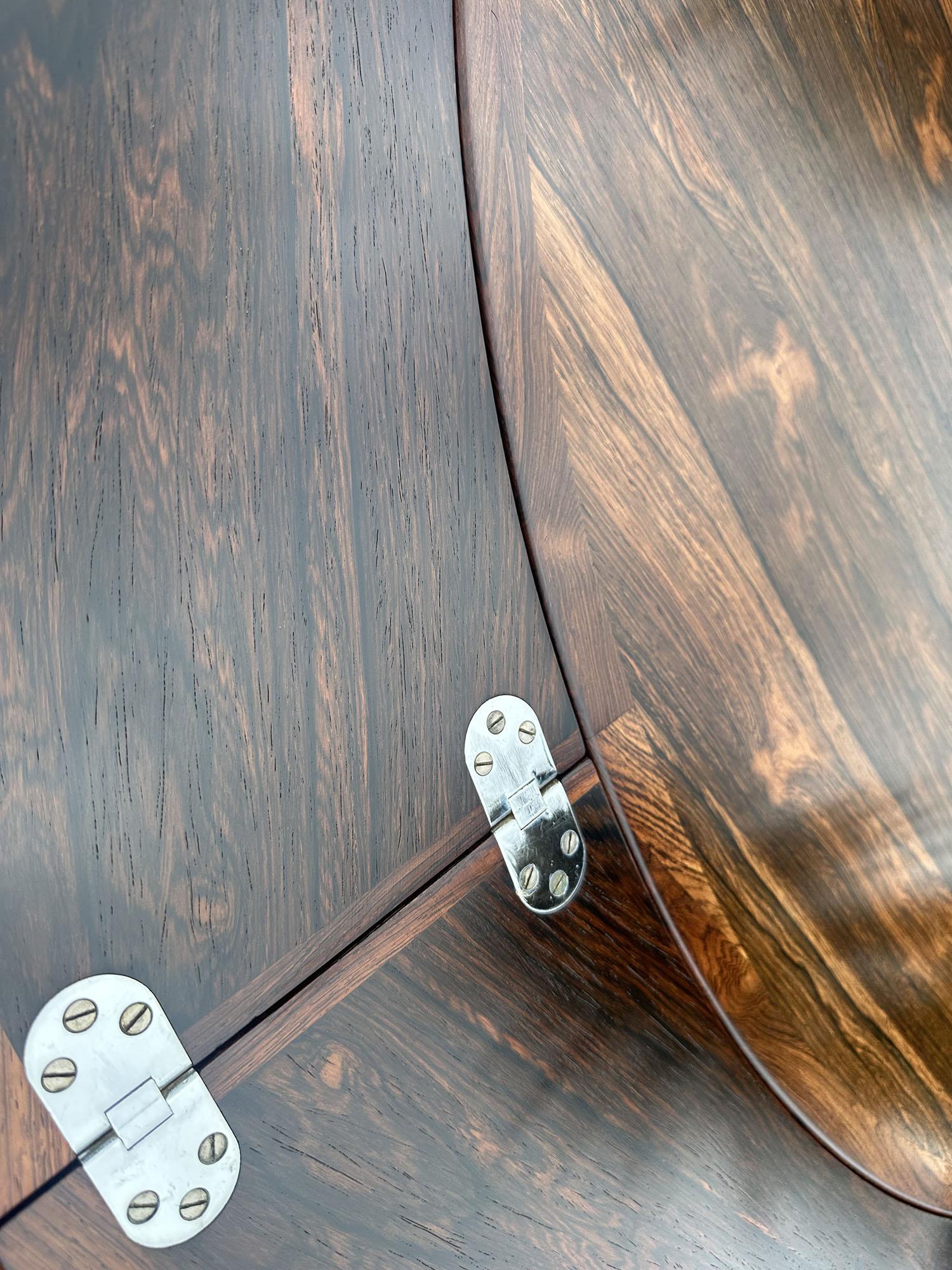 This is a very nice example of this ingenius extending circular dining table, with the more popular center supported chrome base.
in Santos Rosewood (Machaerium Scleroxylon) a species not on the Cites list of endangered species, and therefore no