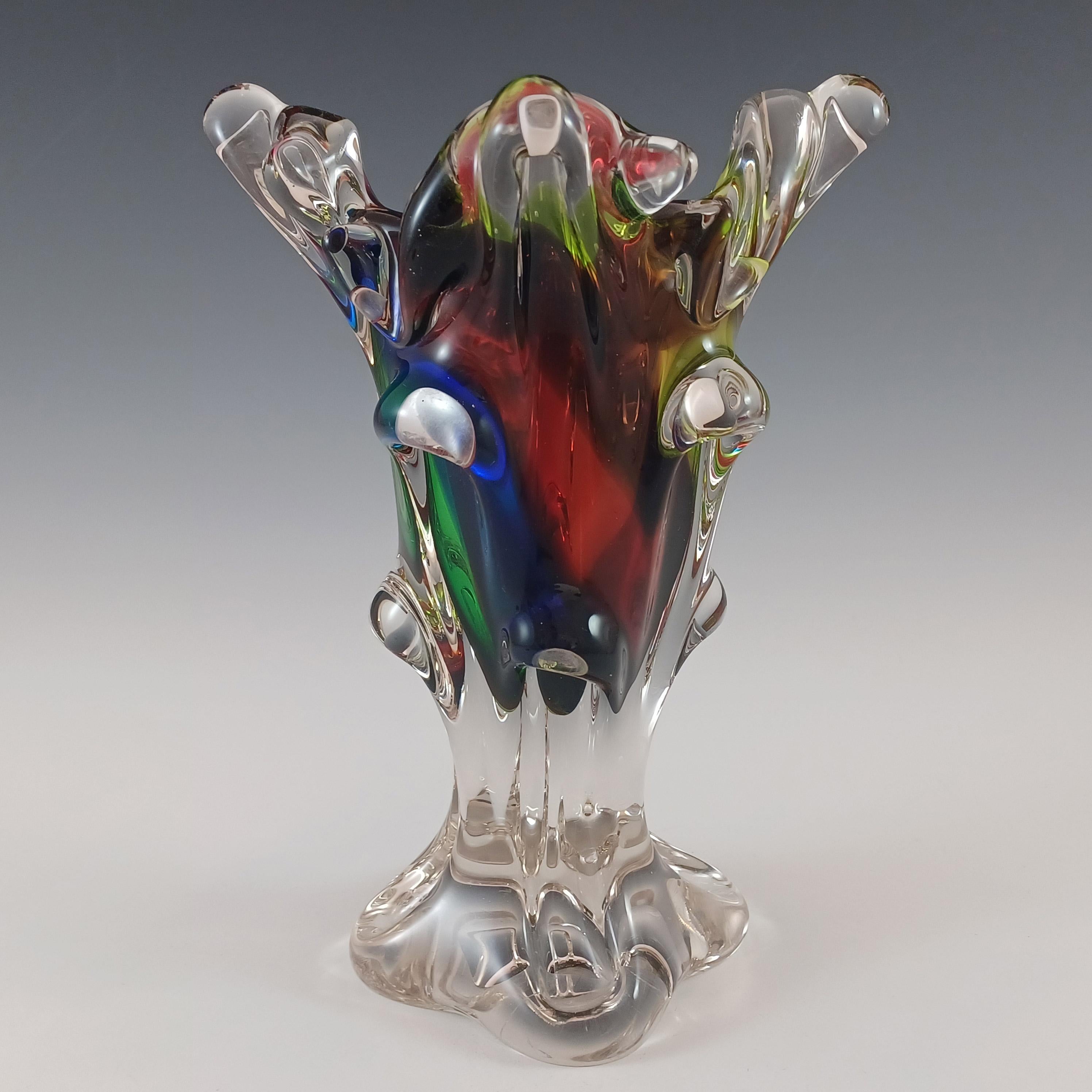 Aquí tienes un jarrón de cristal orgánico, grueso y pesado, con lóbulos arrancados. Fabricado en Japón, probablemente por las cristalerías Sanyu o Iwatsu. En una asombrosa combinación de cristal rojo, azul, verde y amarillo envuelto en cristal